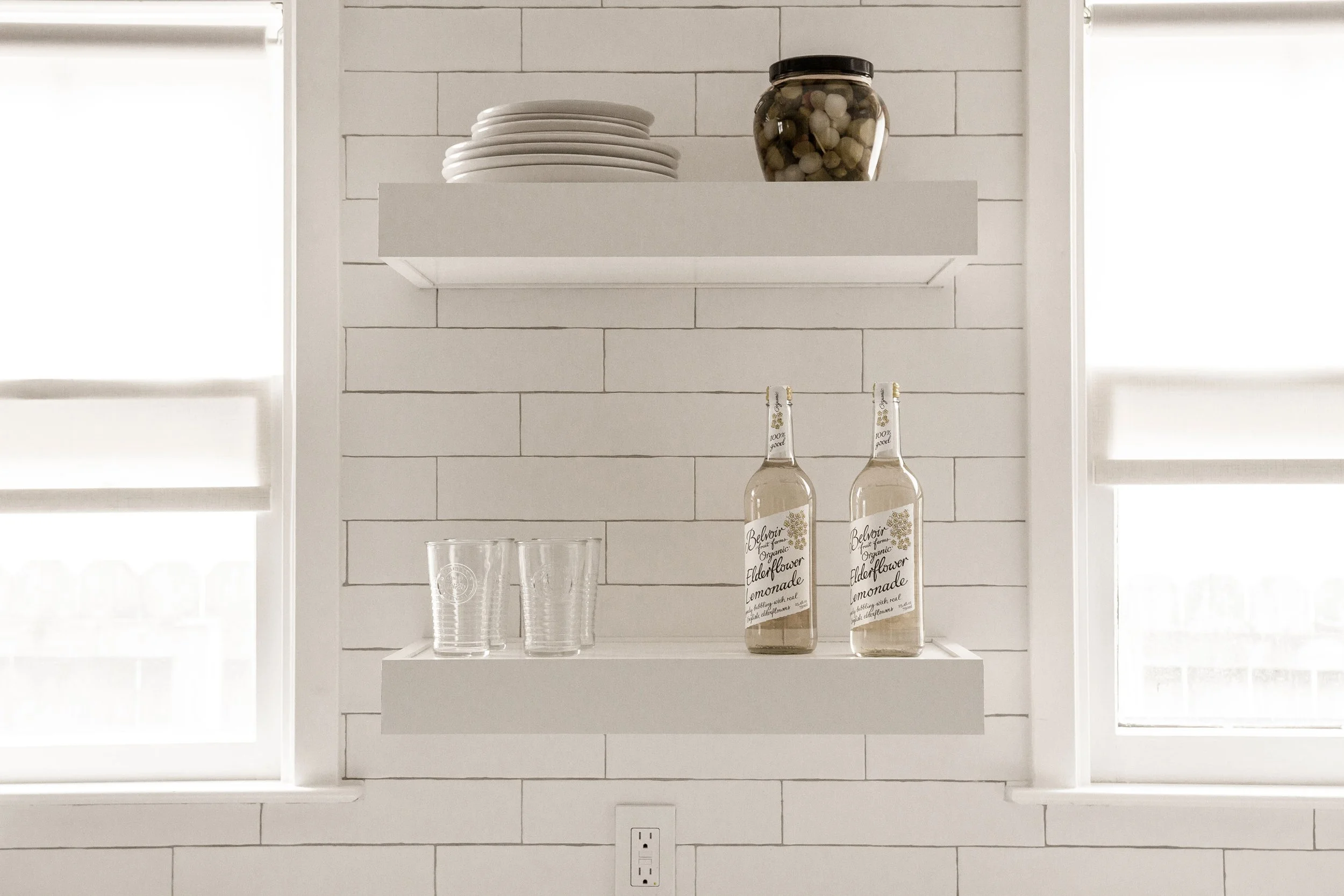 Bright, minimalist kitchen shelves with plates and drinks. Design-build Nashville.