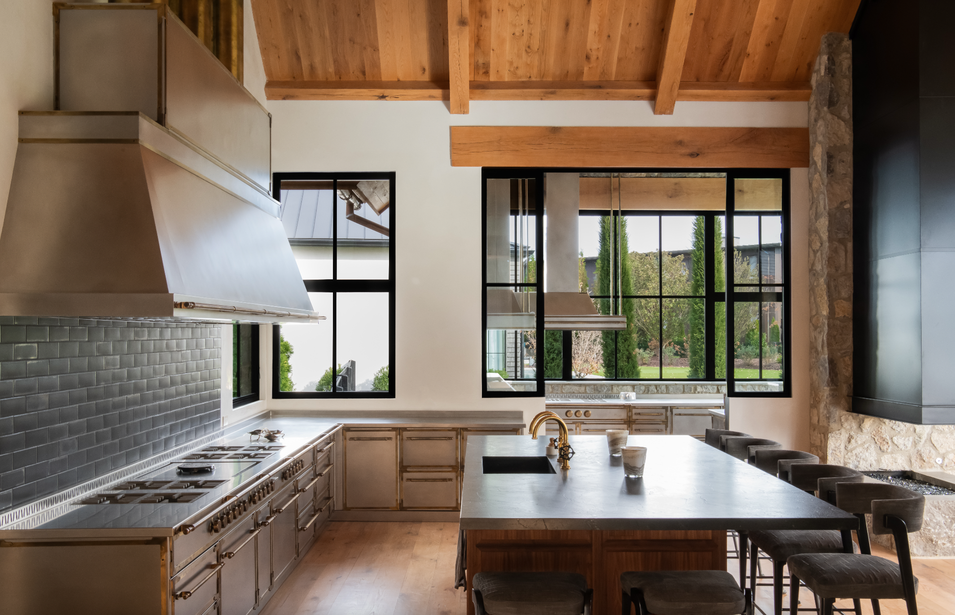 Luxury kitchen in Nashville custom home with wood beams, metal cabinets, and a stone fireplace.
