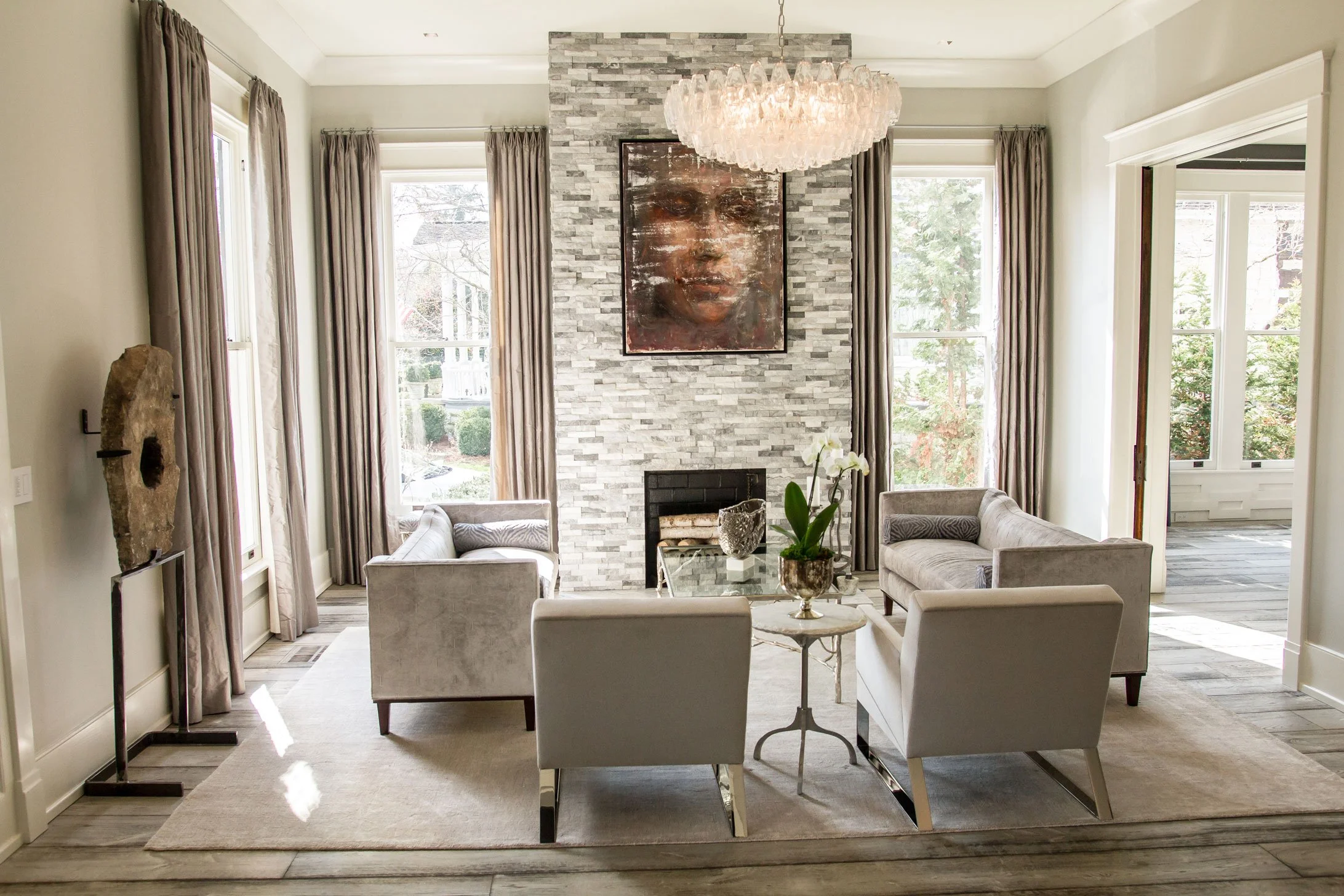 Elegant living room with stone fireplace, artwork, and chandelier. Luxury home builder Nashville.