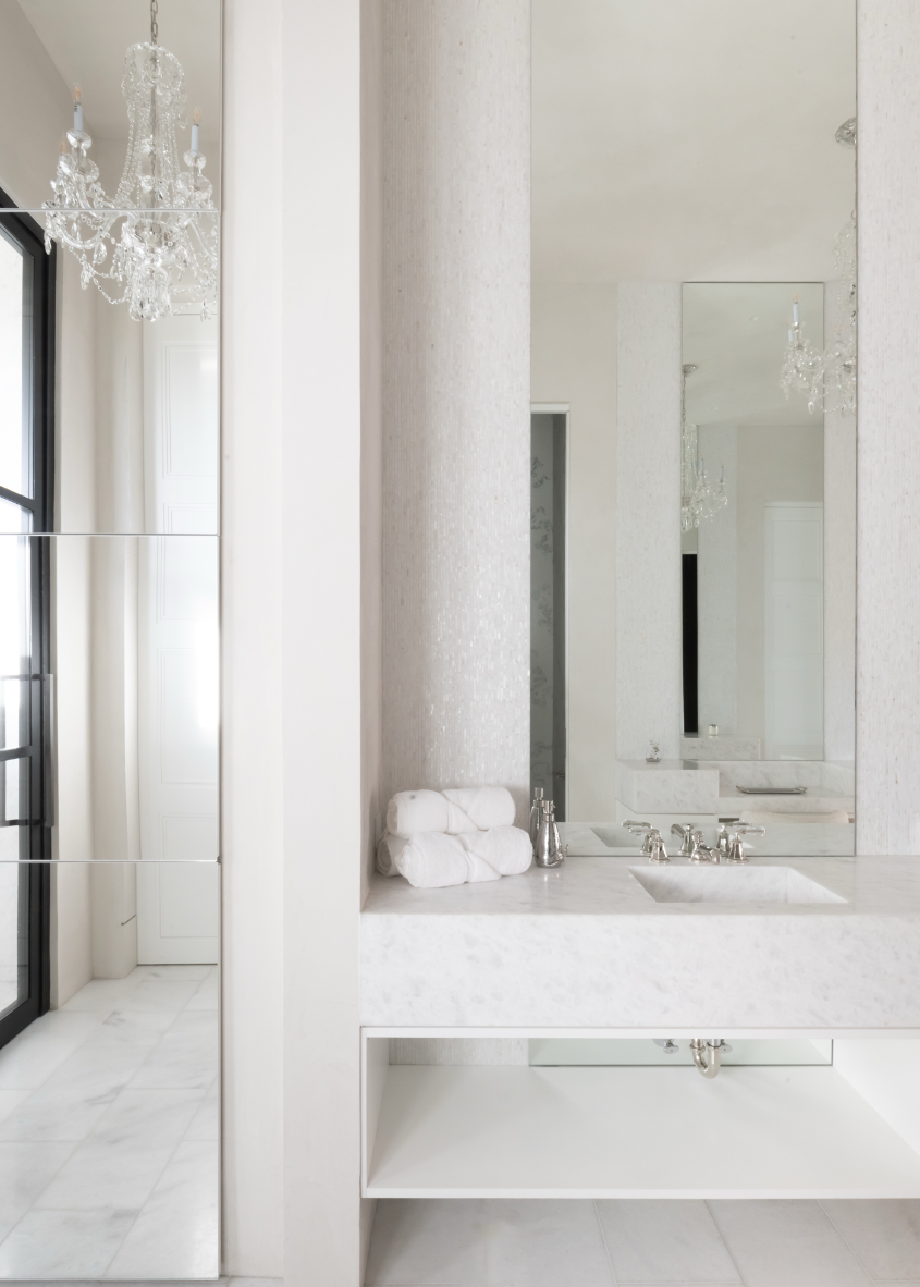 Elegant all-white bathroom in Nashville custom home featuring marble countertop and crystal chandelier.