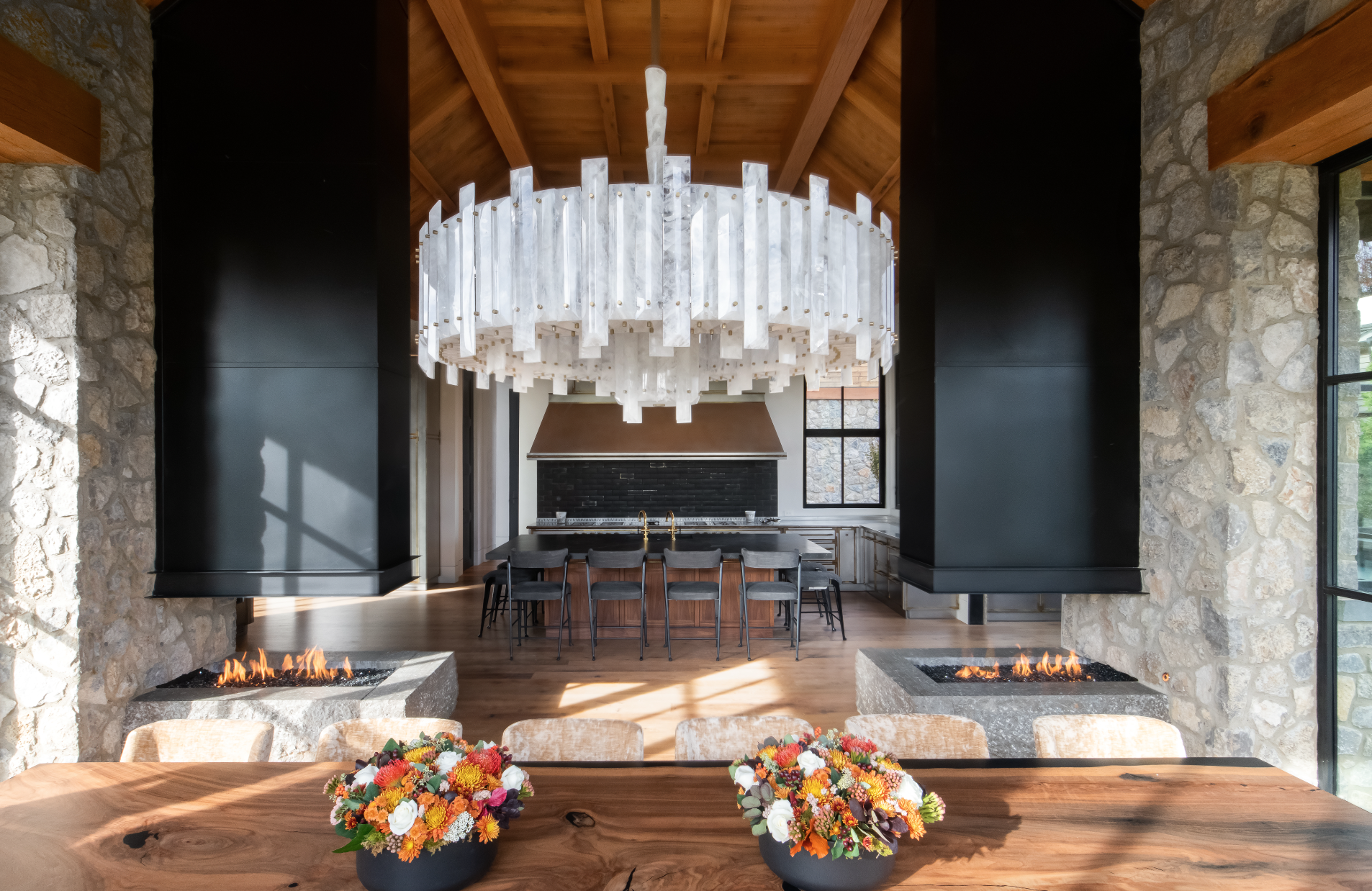 Open-concept custom home Nashville design featuring dining area, stone fireplace, and quartz chandelier.