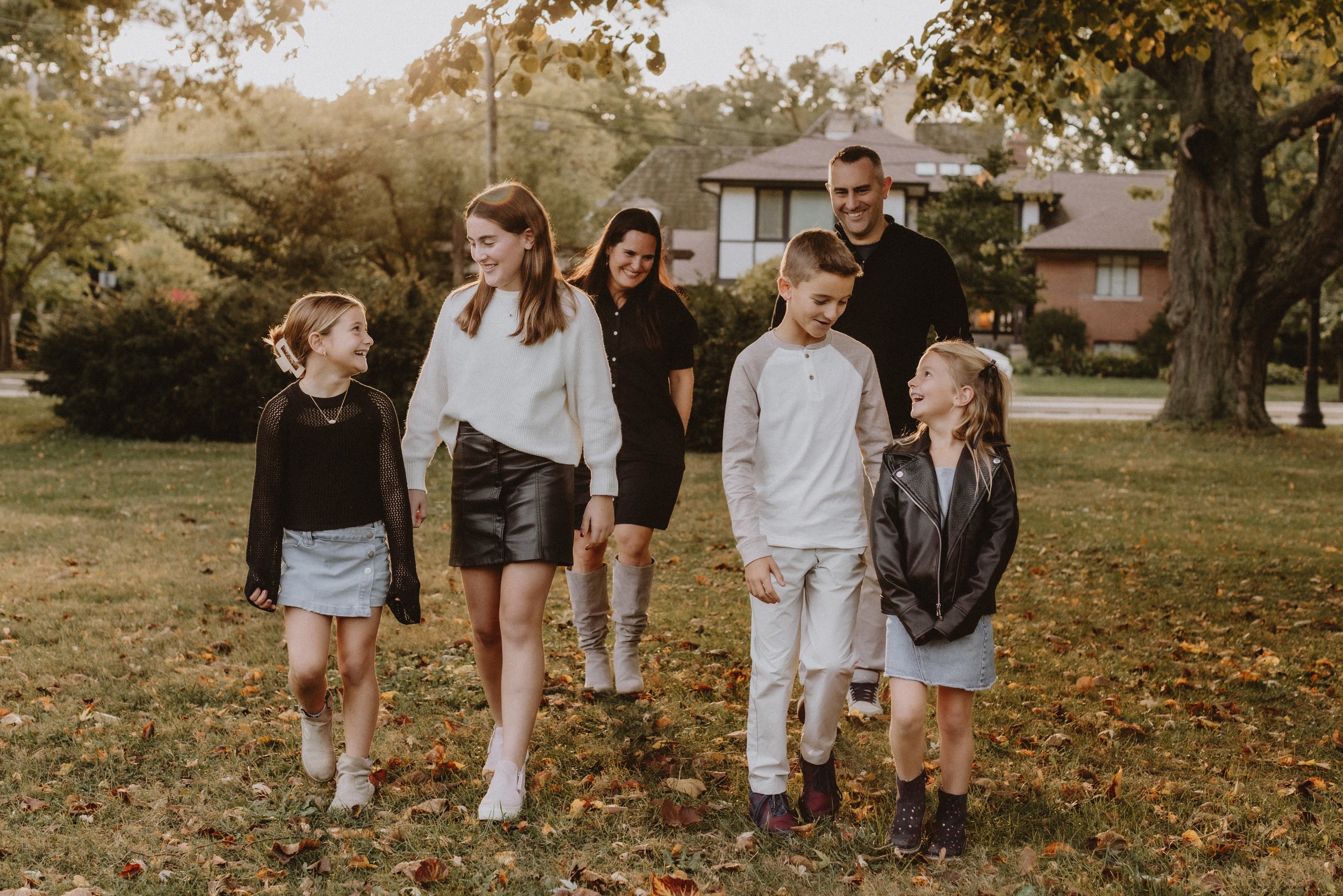 A family walking together in a park during fall, smiling and enjoying each other's company. Lifestyle family photography.  Shot at Lighthouse Beach Park, Evanston. Grosse Point Lighthouse near Northwestern University