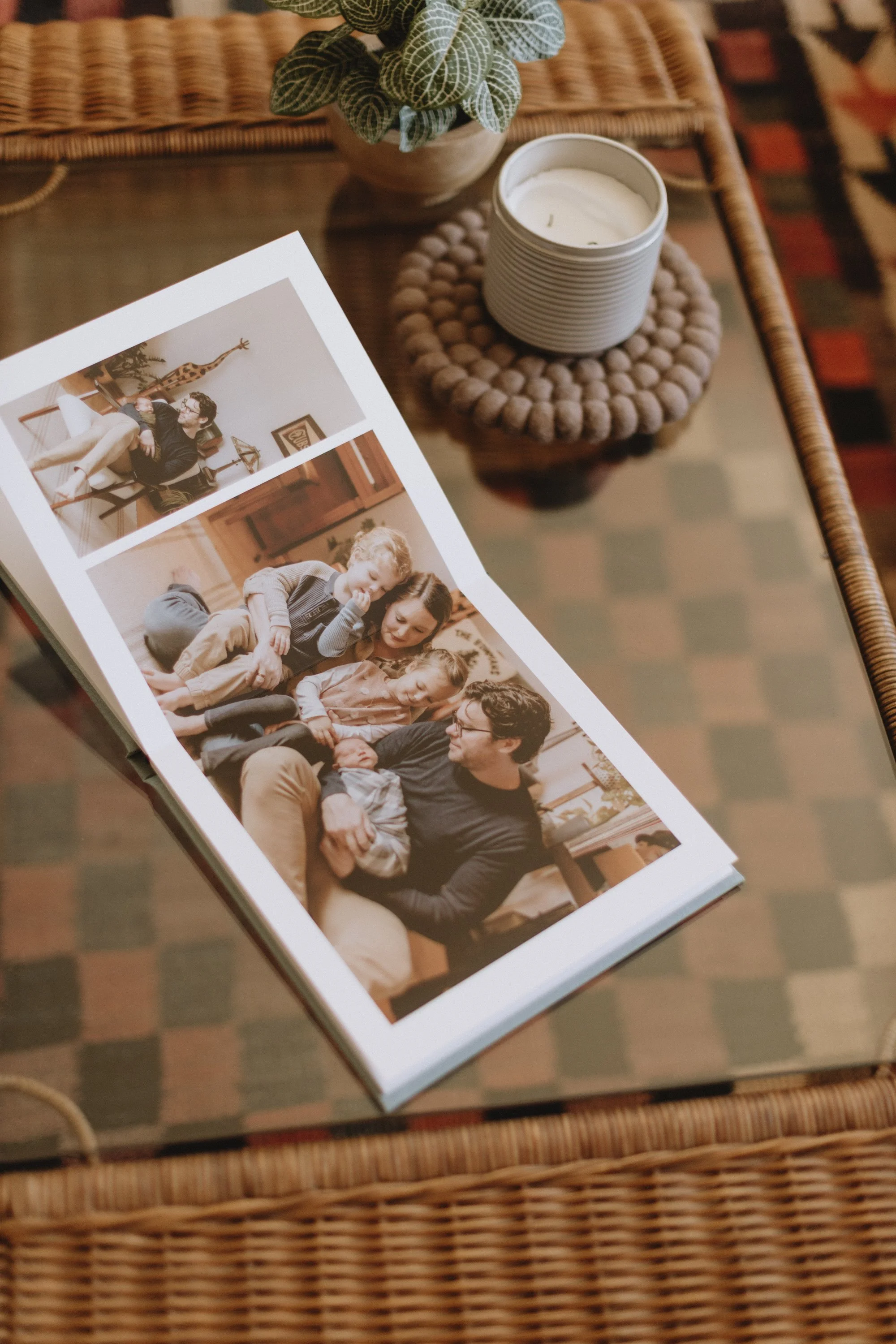 Photograph of a printed photo collage on a table, showing scenes of a man, a woman, and two children in a cozy indoor setting with warm lighting.