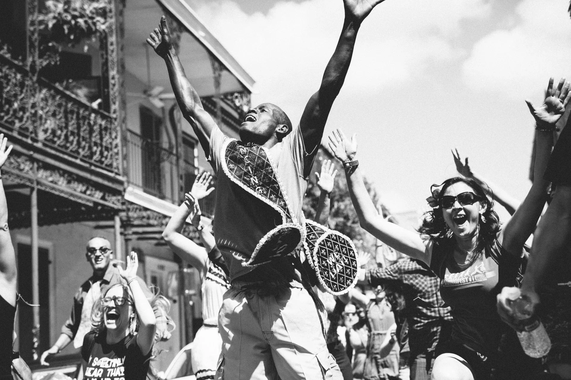 People celebrating outdoors, dancing and raising their arms, with one person wearing sunglasses and a printed T-shirt.  Documentary Photography Chicago IL, Erin Drewitz Photography