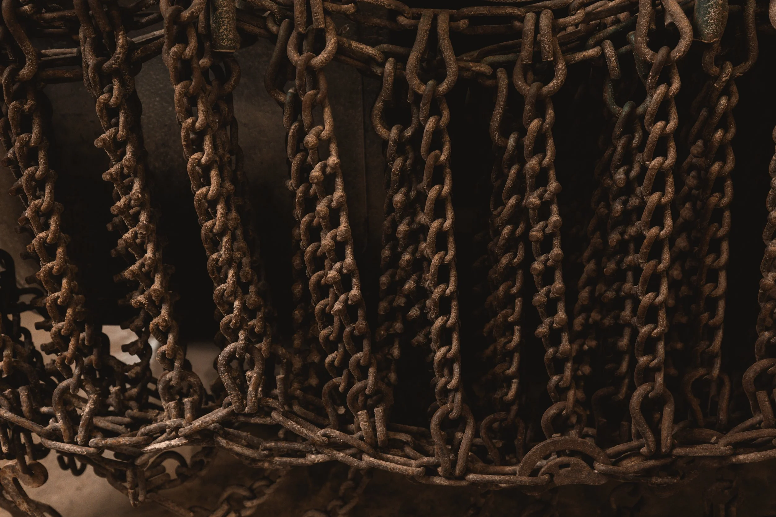 A collection of rusted metal chains hanging and piled together.