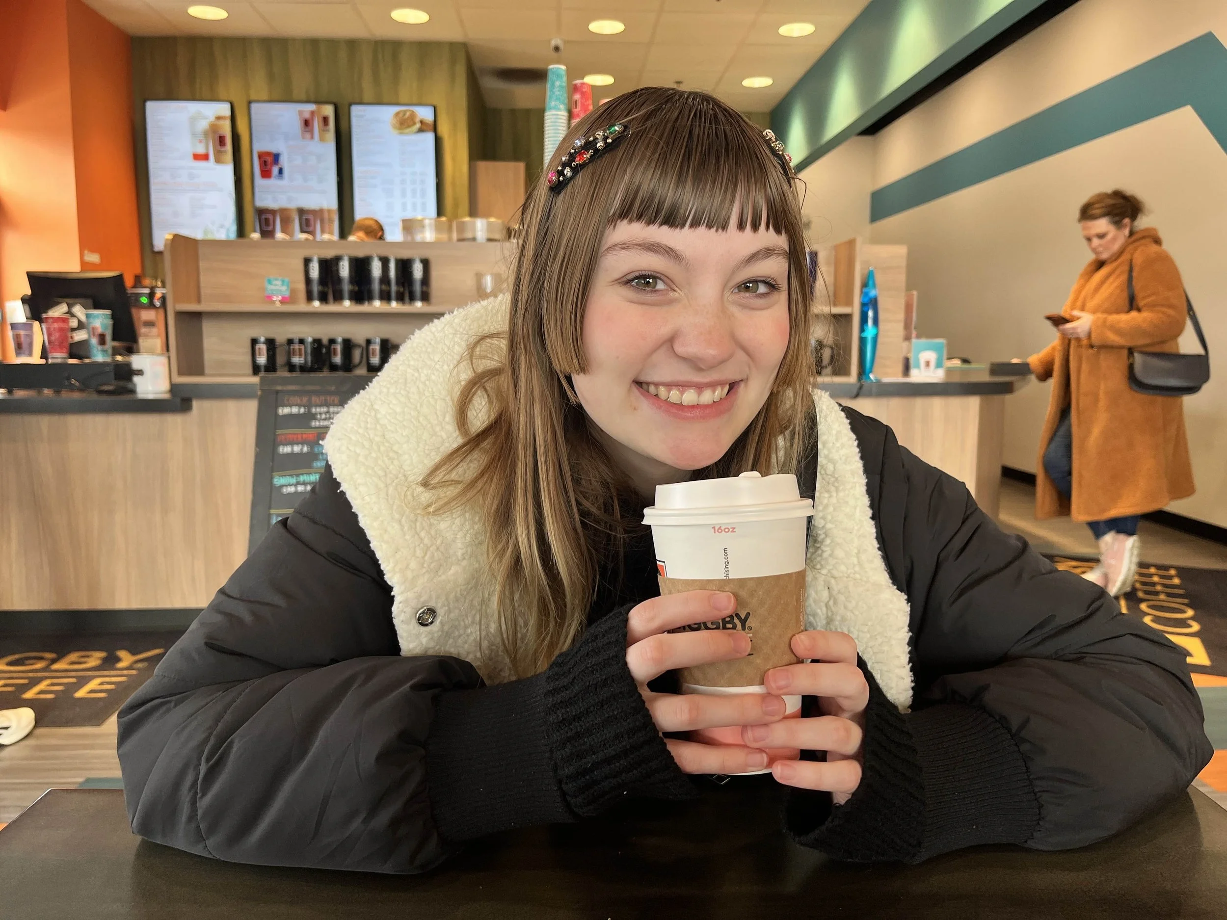 Alli Johnson holding a coffee cup and smiling.