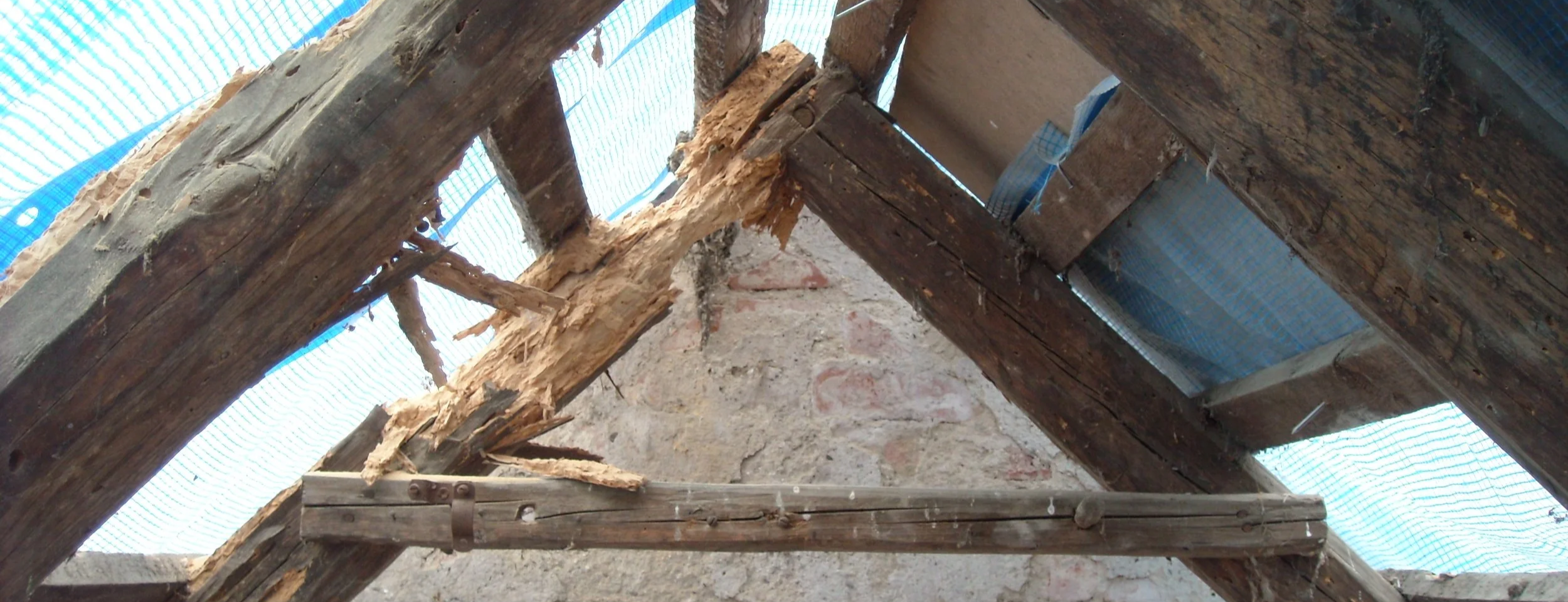 Ein alter Dachstuhl mit Sparren die durch den Hausbock stark geschaedigt wurden