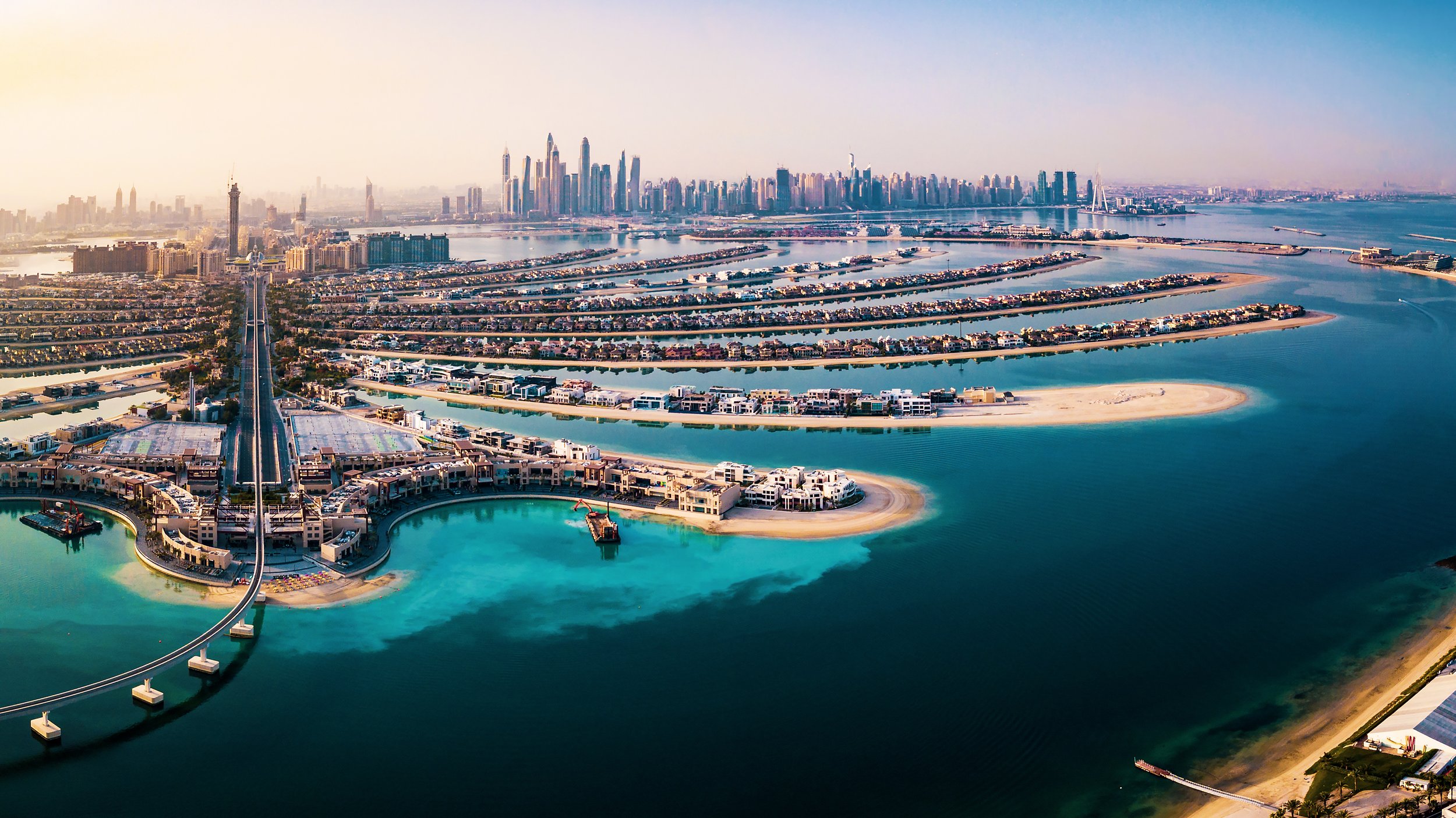 Aerial view of Dubai Marina with artificial islands, water canals, skyscrapers, and the city skyline in the background