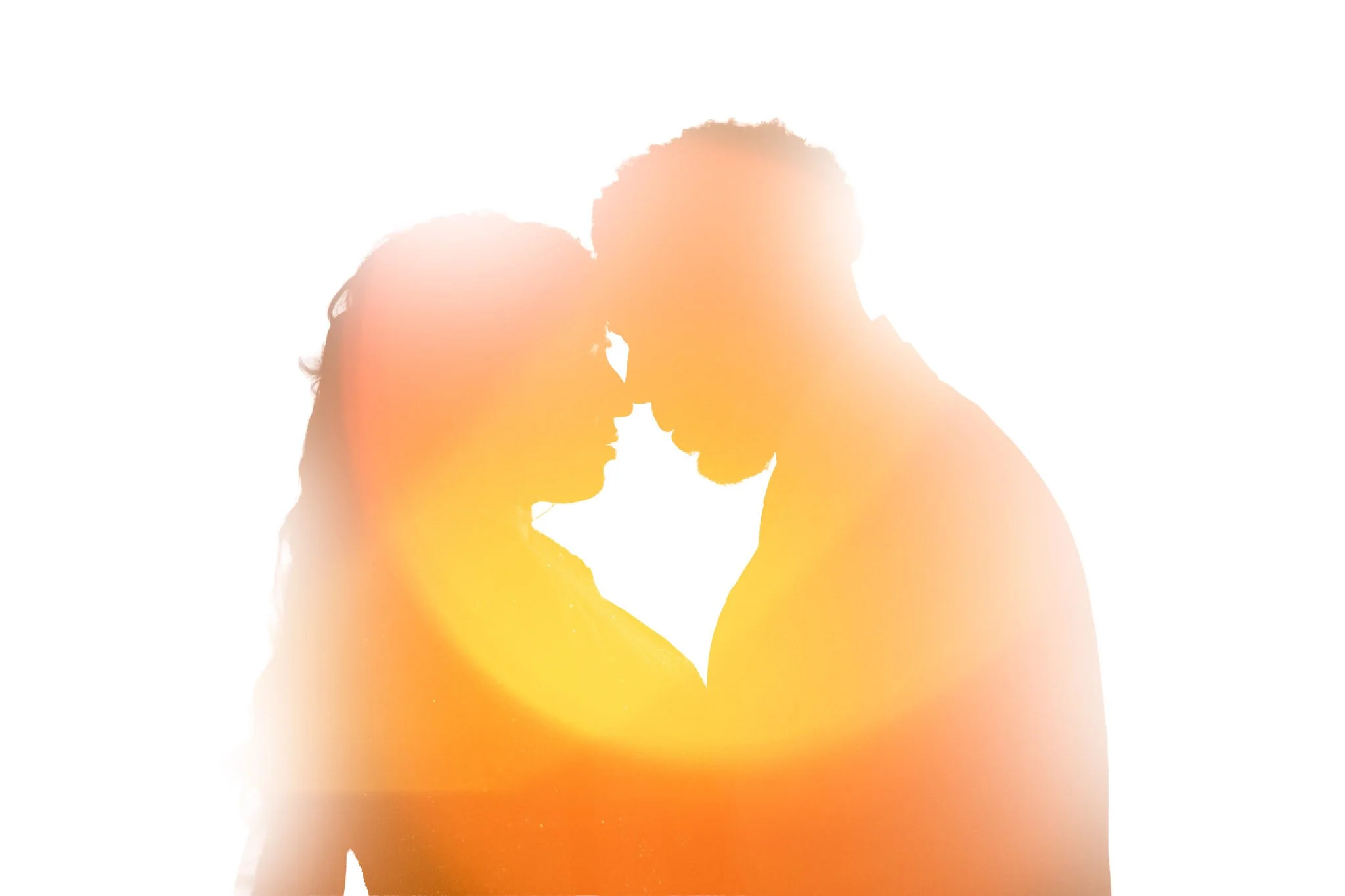 Silhouette of a couple touching foreheads with a warm, glowing light behind them.
