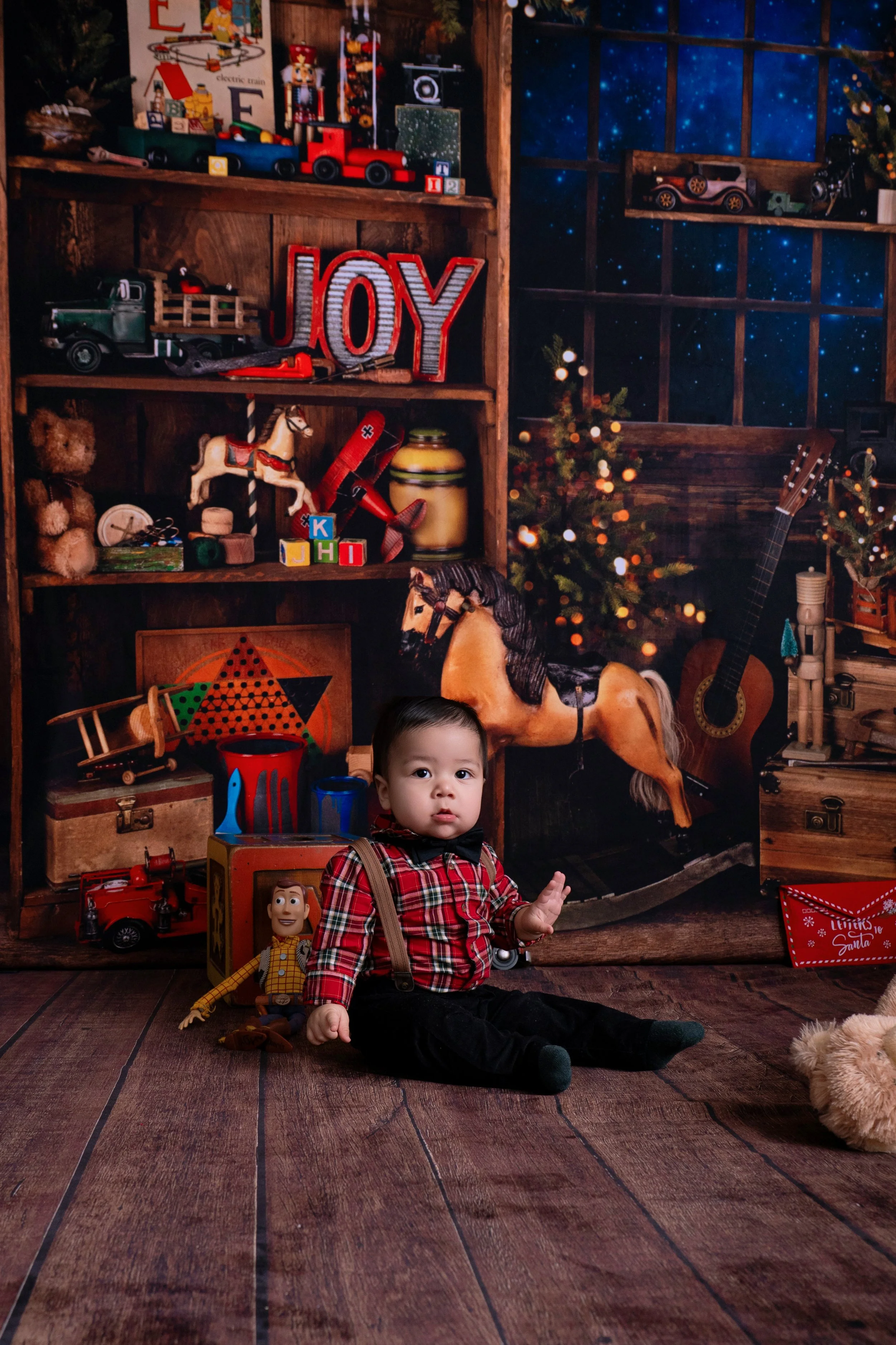Little boy sitting on the floor in santas workshop surrounded by toys in Modesto CA
