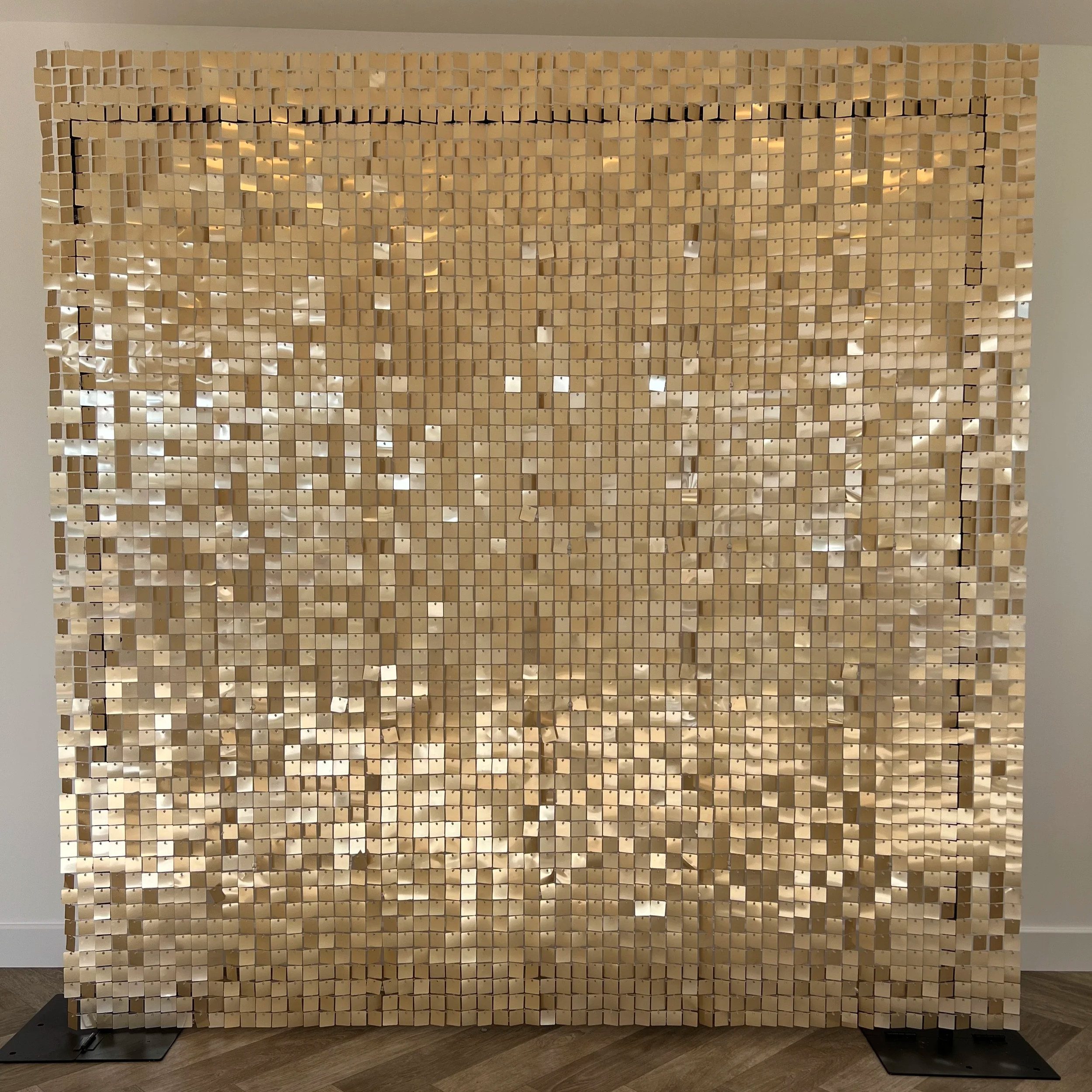 A decorative wall installation made of numerous small, beige, square tiles arranged in a grid pattern.
