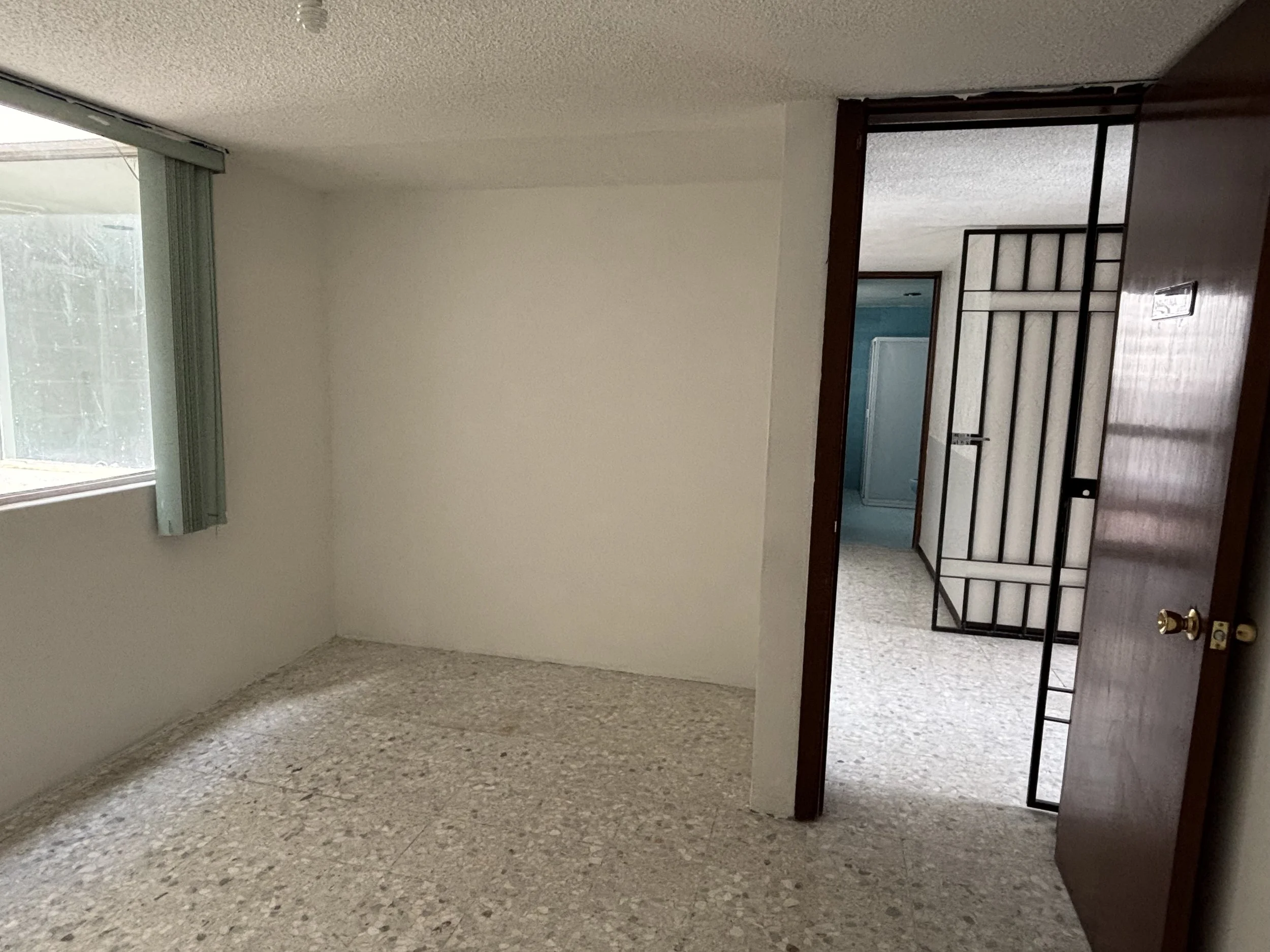 Interior room with a window and an open door leading to a hallway or another room.