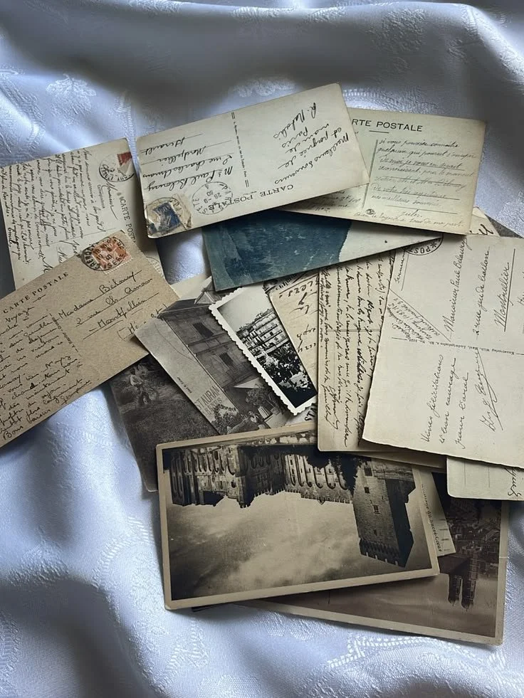 A collection of vintage postcards and photographs spread out on a white fabric surface.