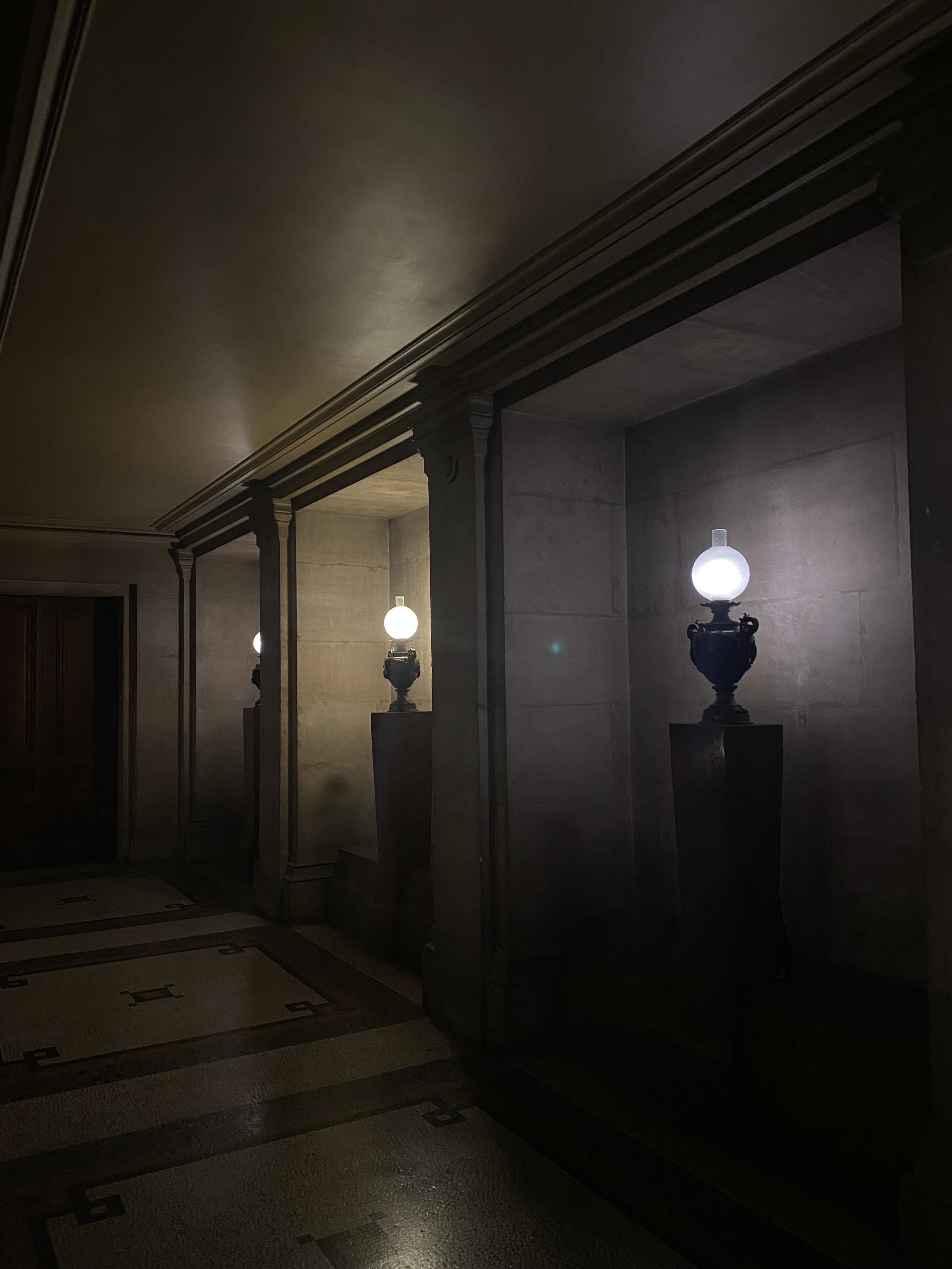 Dimly lit interior with dark wood furniture, decorative lamps, and patterned tile flooring.