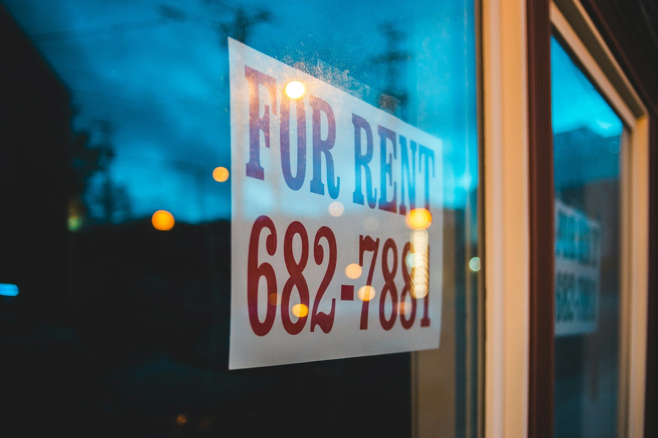 Sign in window advertising a property for rent with contact phone number