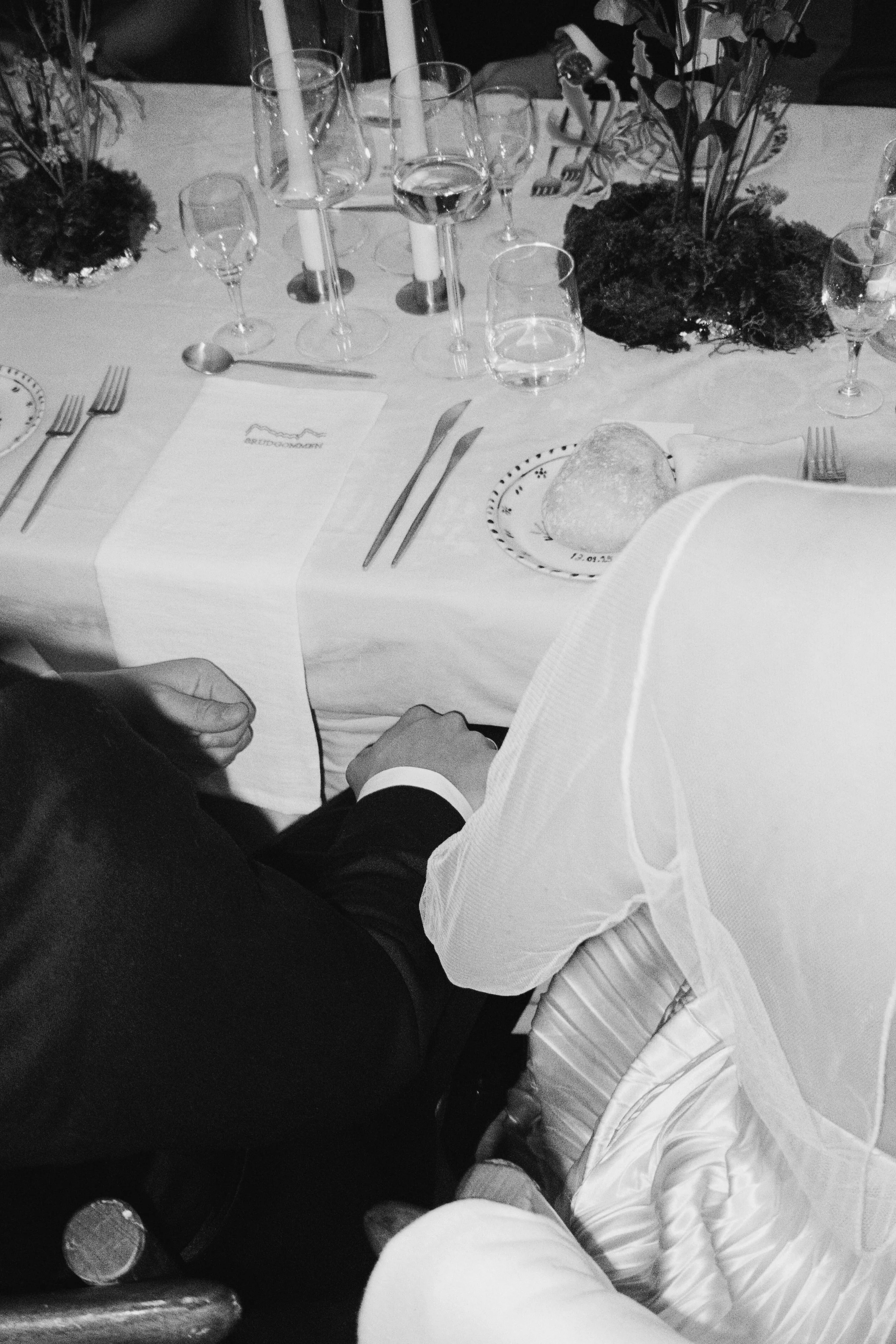 A formal dinner table set with glassware, plates, and cutlery, decorated with floral arrangements.