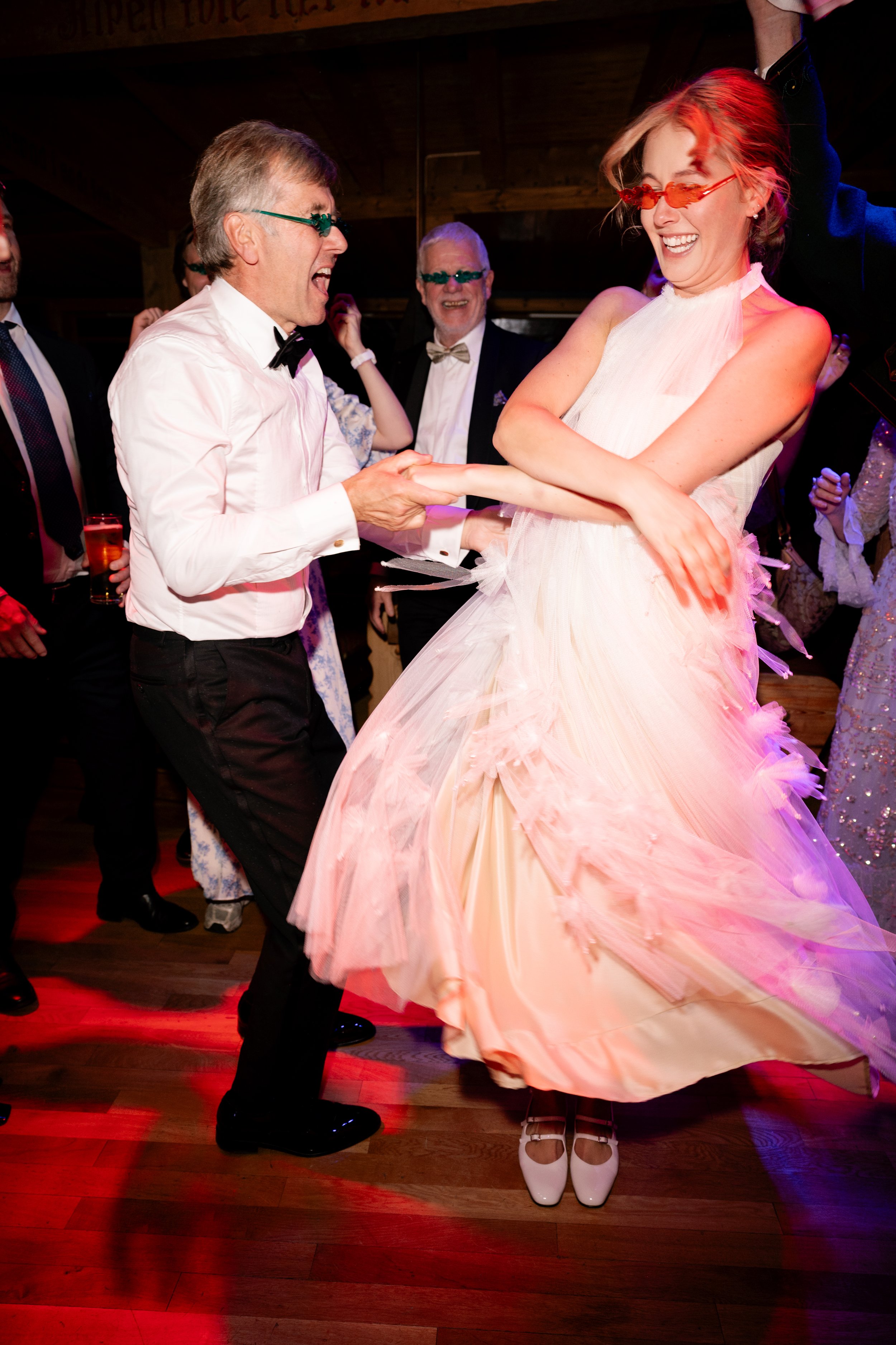 Couple dancing at a wedding reception with guests watching and smiling.