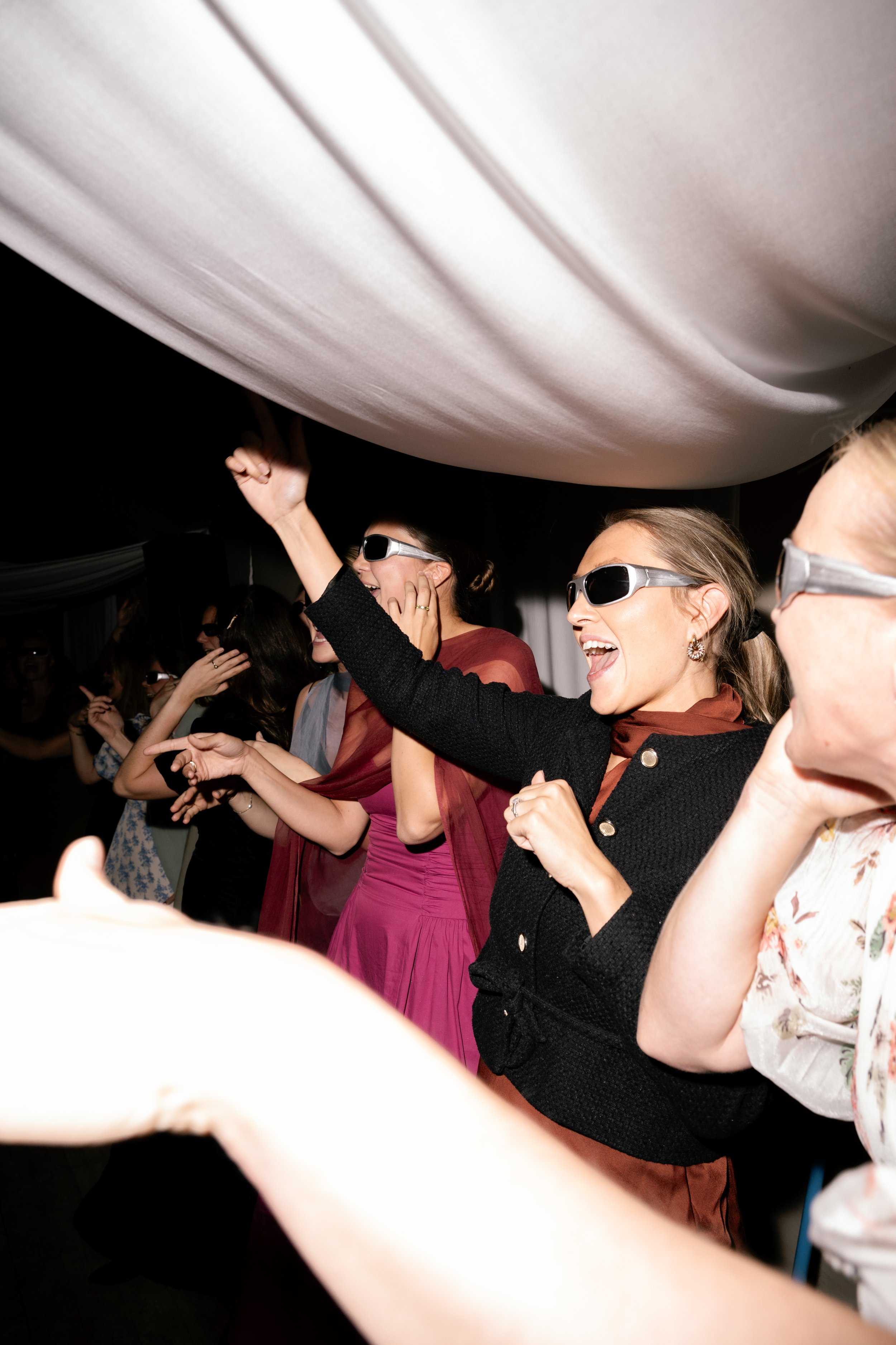 Women wearing sunglasses dancing and having fun at a party.