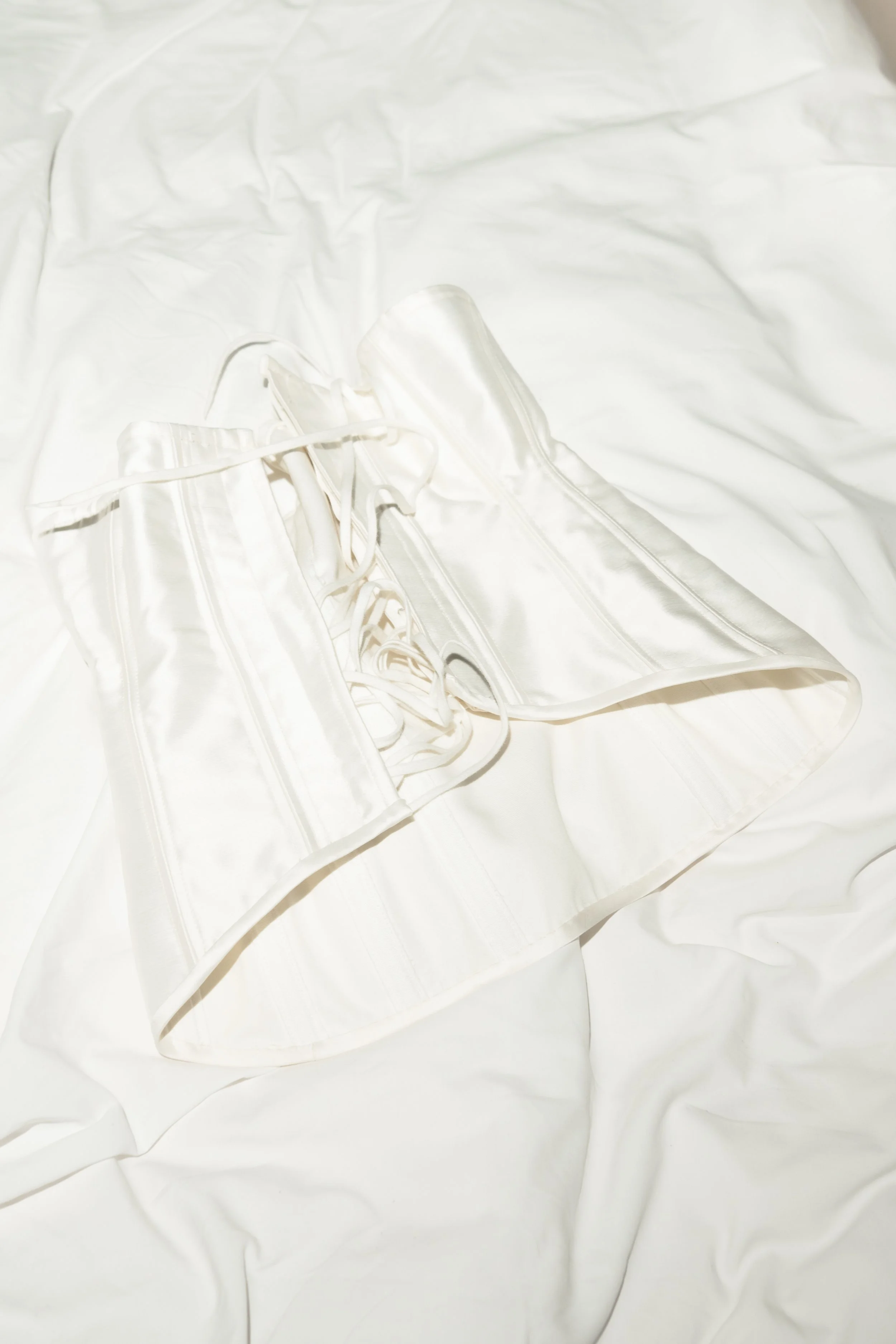 A white satin corset with lace-up front and zipper.