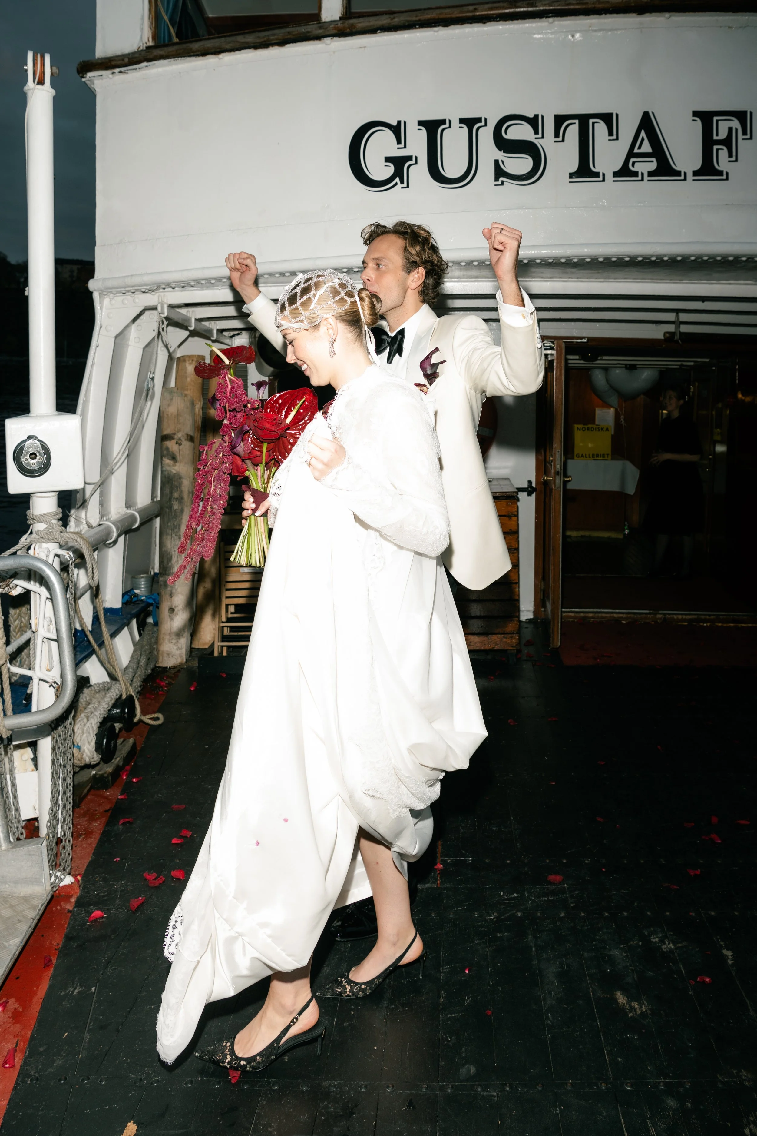 A bride and groom dancing on a boat during their wedding celebration at night.