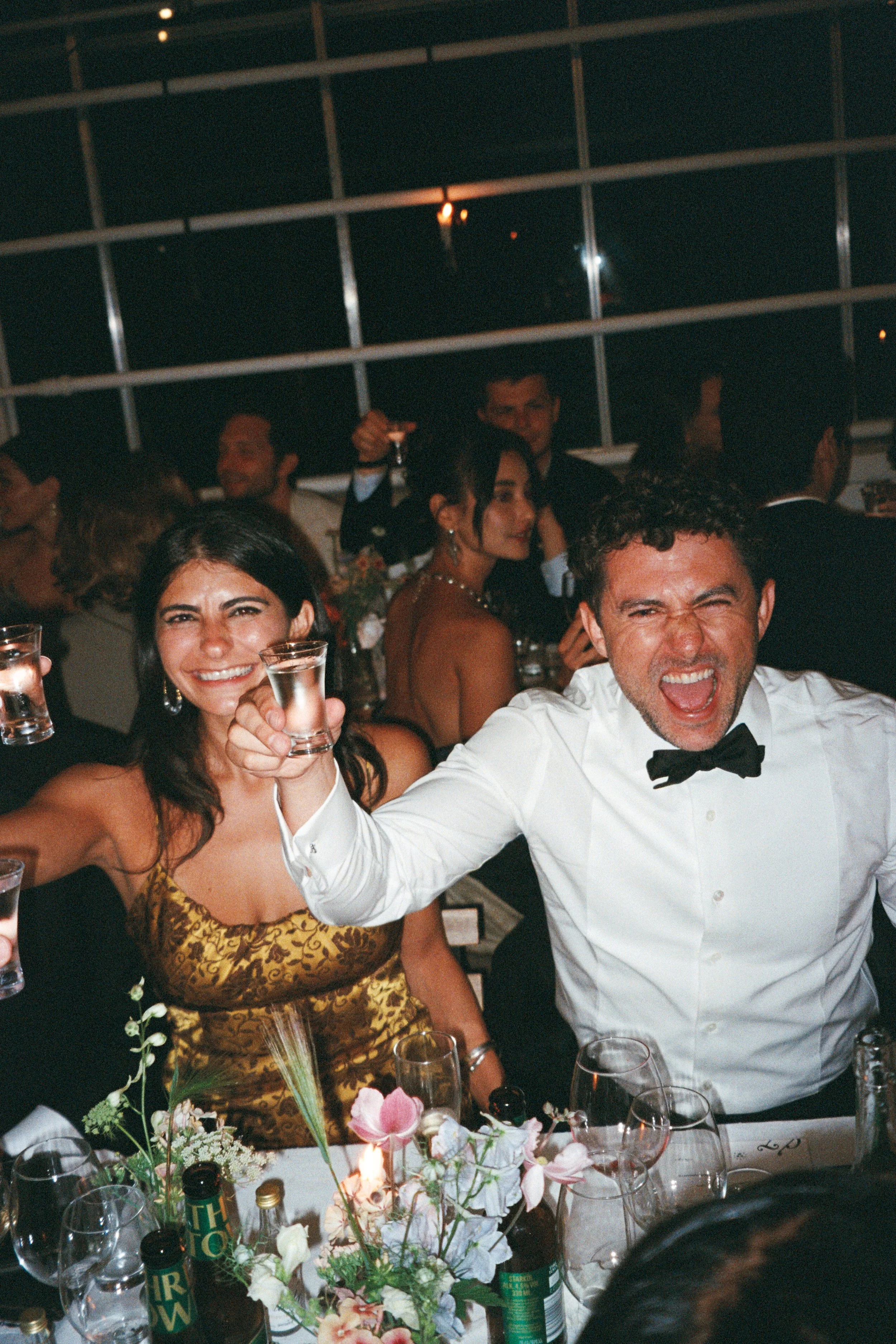 People at a formal celebration raising glasses for a toast, smiling and enjoying the event.