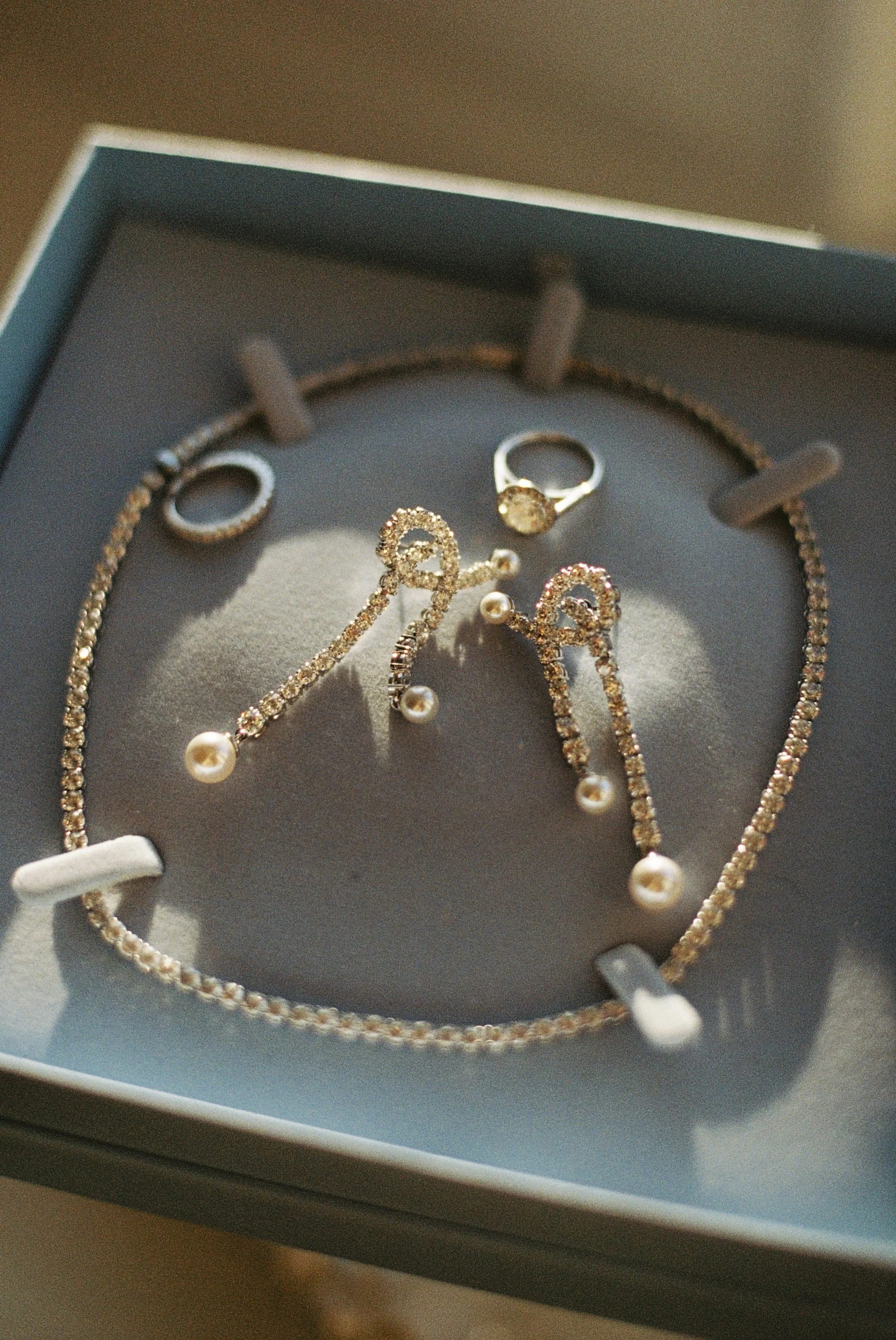 A set of pearl and diamond jewelry, including a necklace, a ring, and earrings, displayed in a jewelry box.