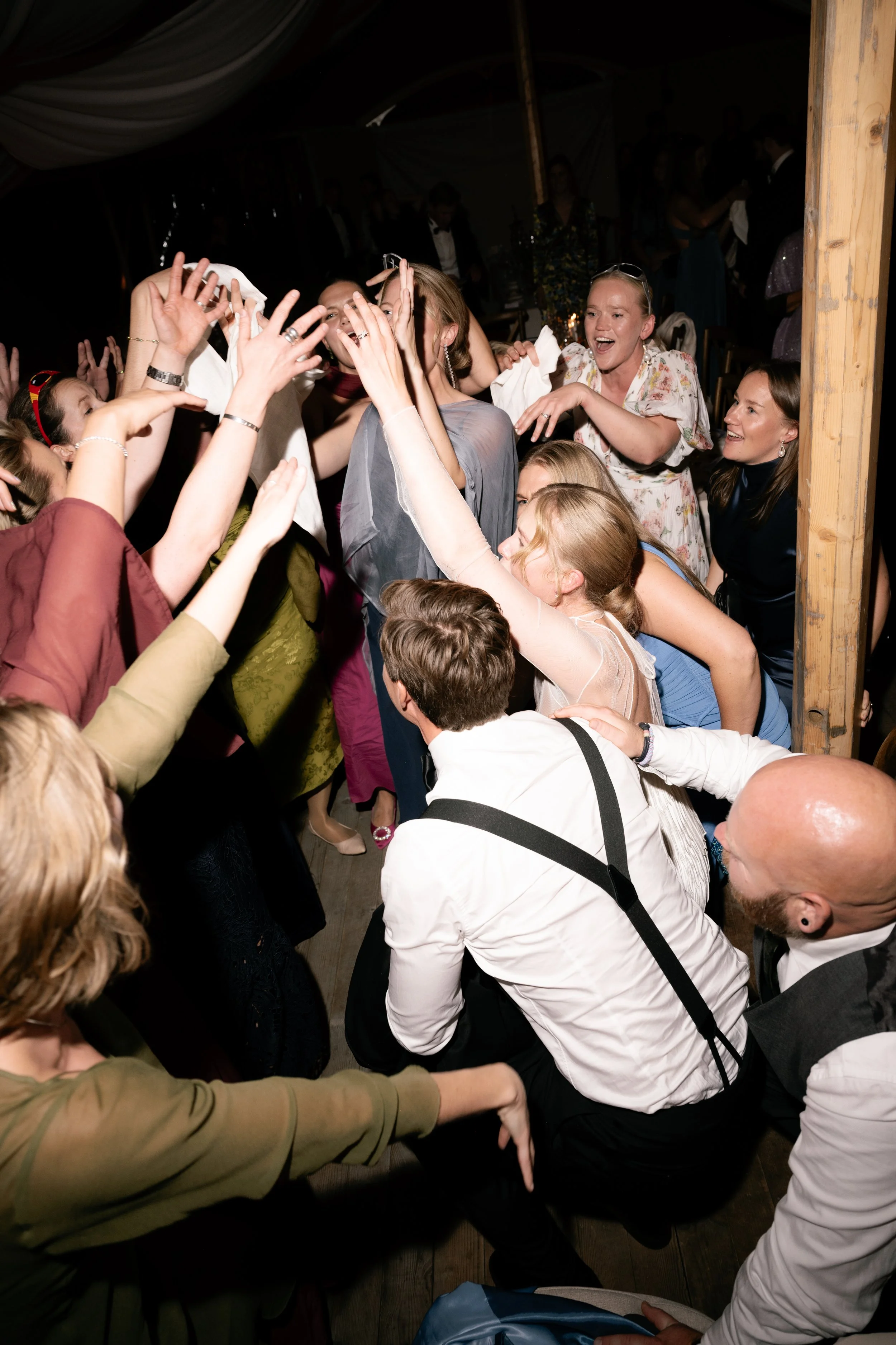 A lively group of people dancing and having fun at a party or celebration in a tented venue.