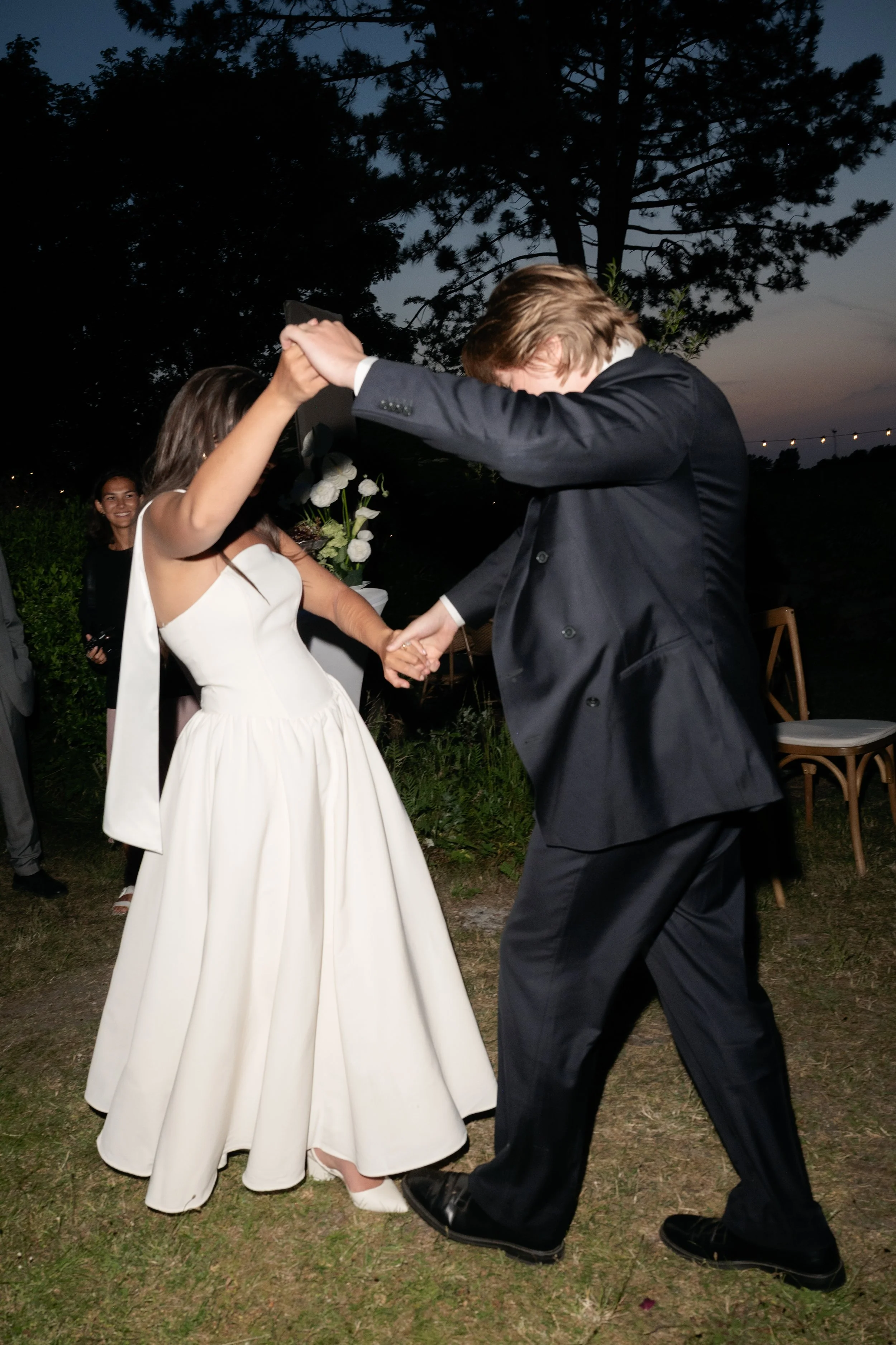 A bride and groom dancing during an outdoor wedding reception at dusk
