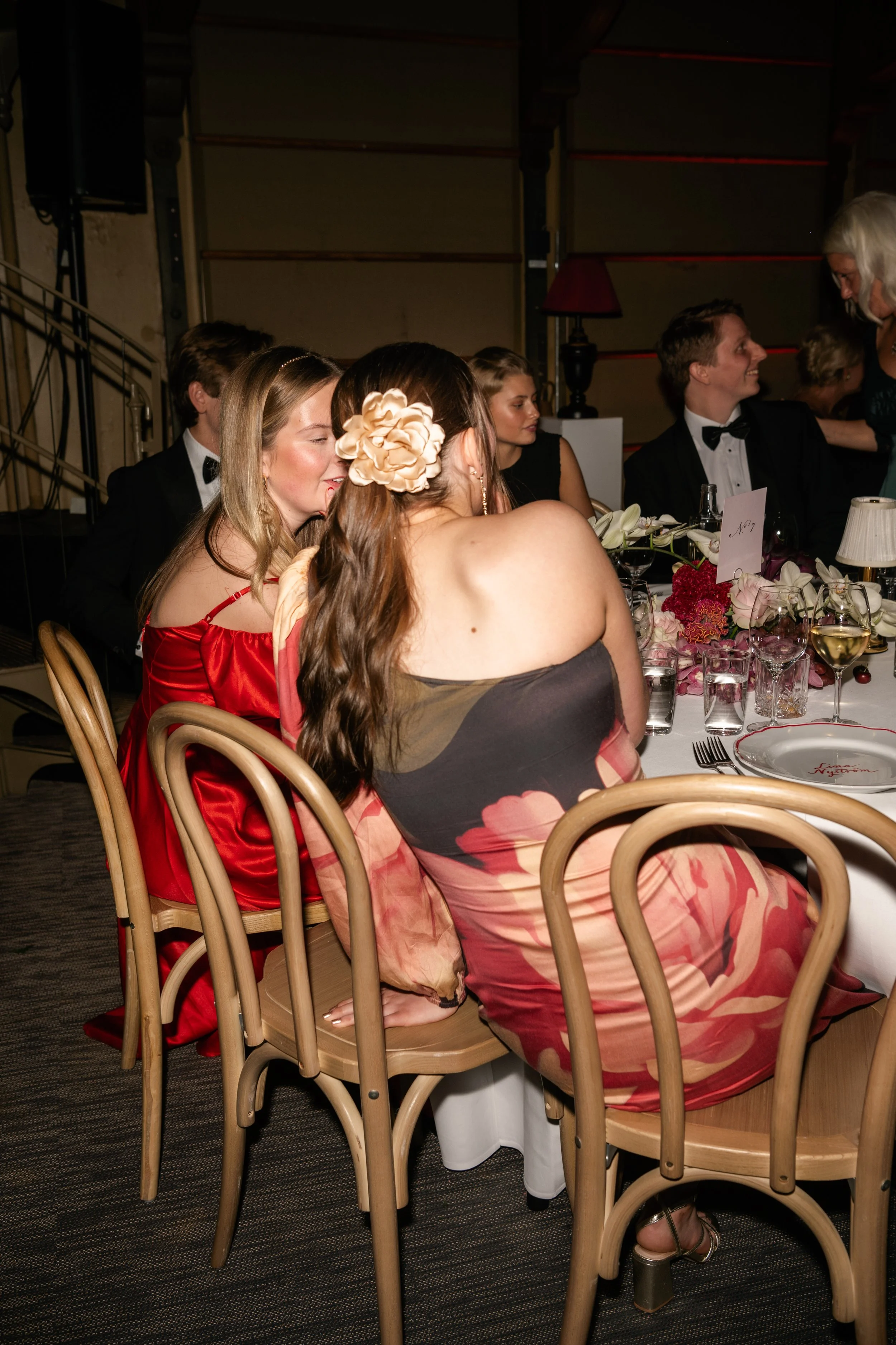 Group of people dressed in formal attire sitting around a table at a wedding or elegant event.