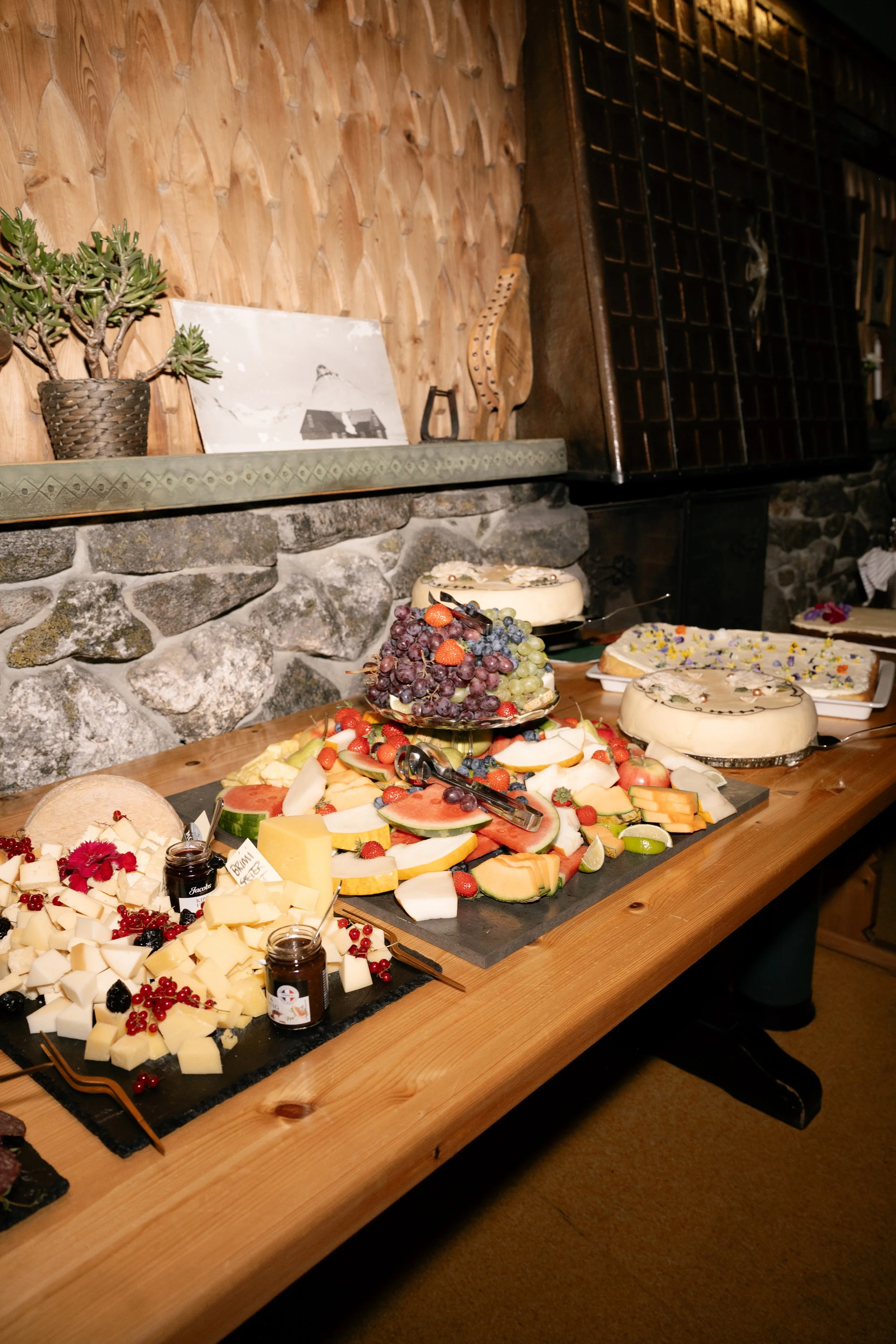 A cheese and fruit platter with grapes and berries, and cheesecakes decorated with flower petals.