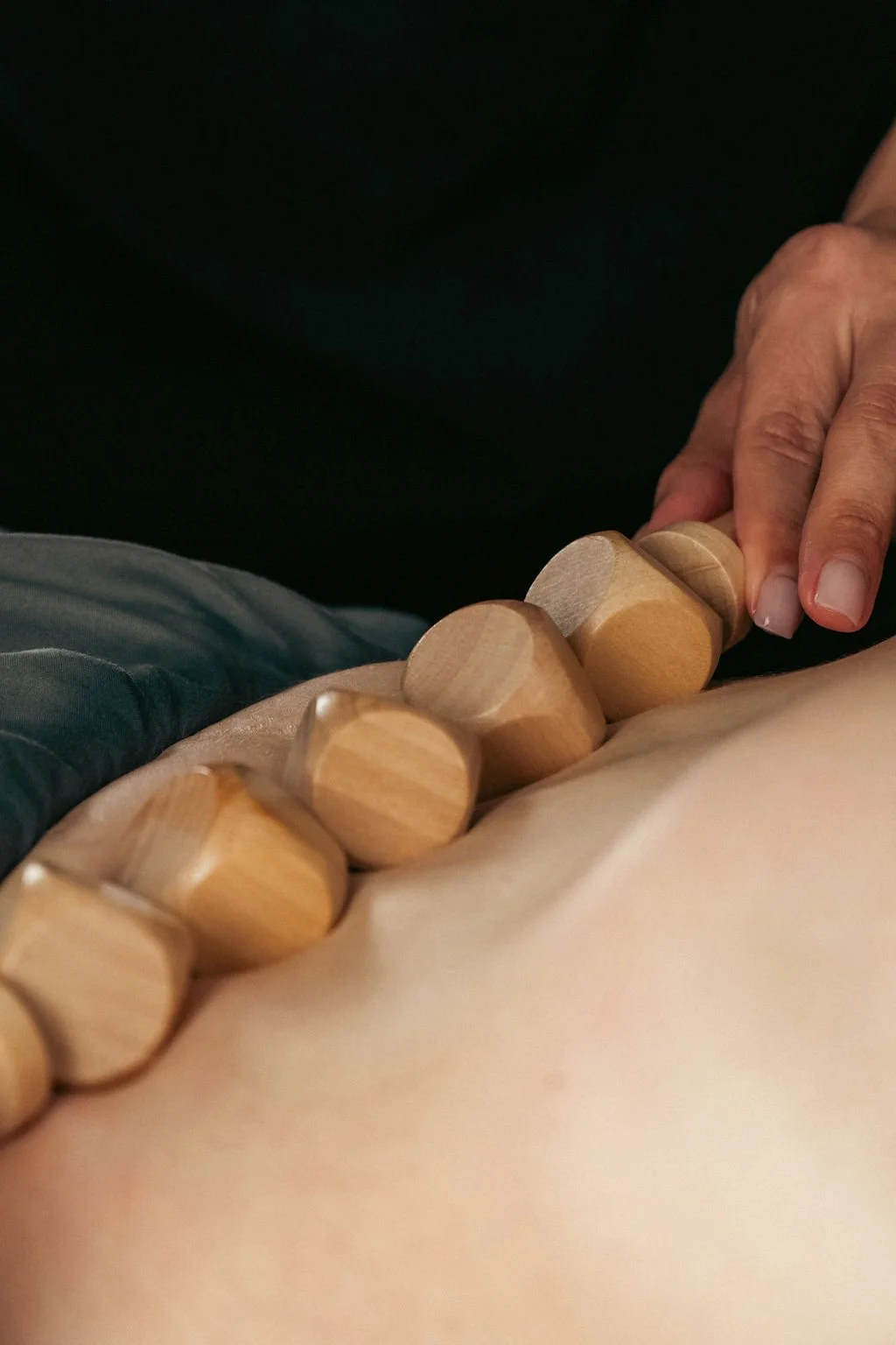 Close-up of hands using a wooden massage tool during a therapeutic session