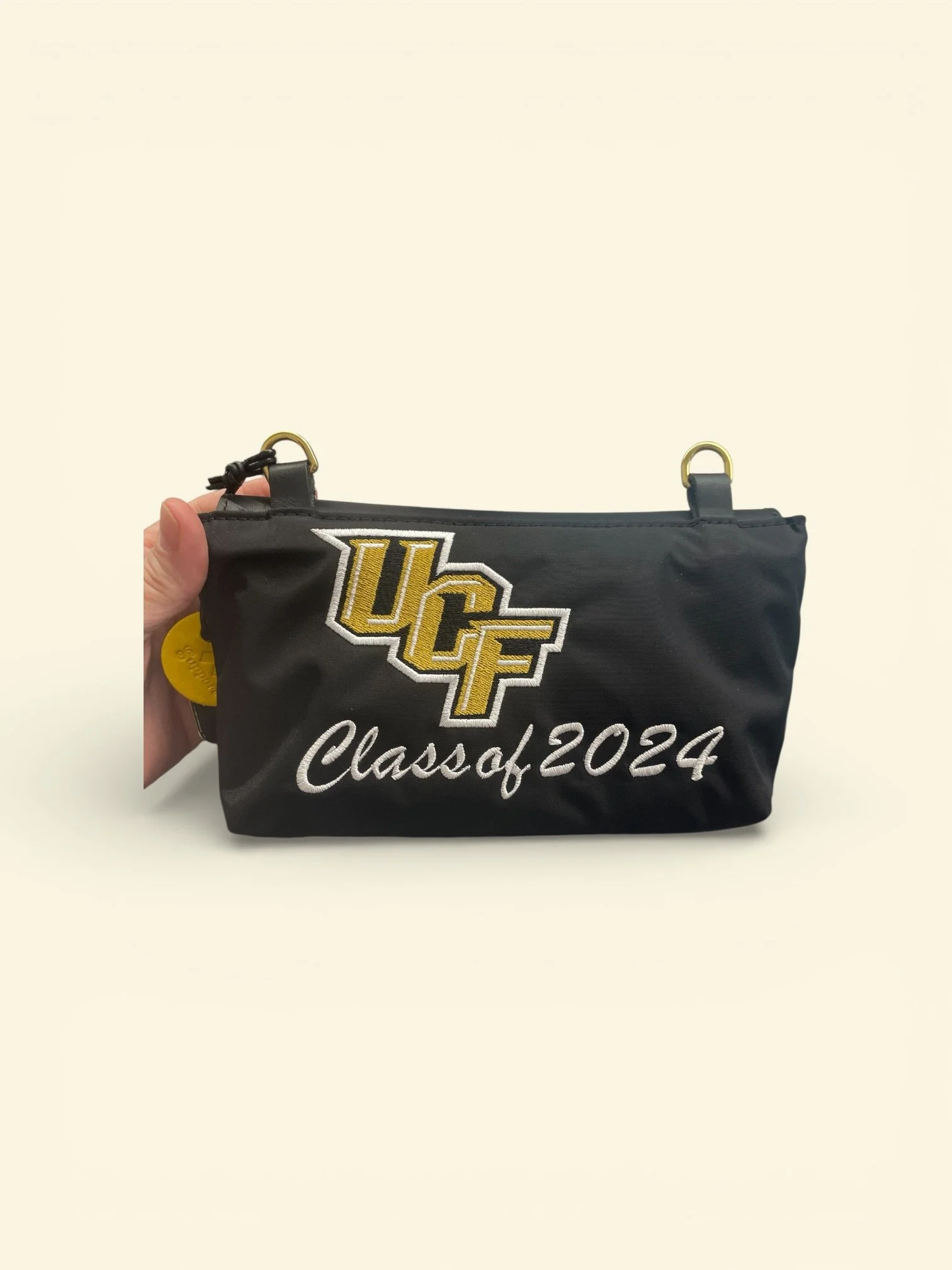 Black UCLA-themed pouch with embroidered yellow and white UCLA logo and 'Class of 2024' text, held by a hand against a plain background.
