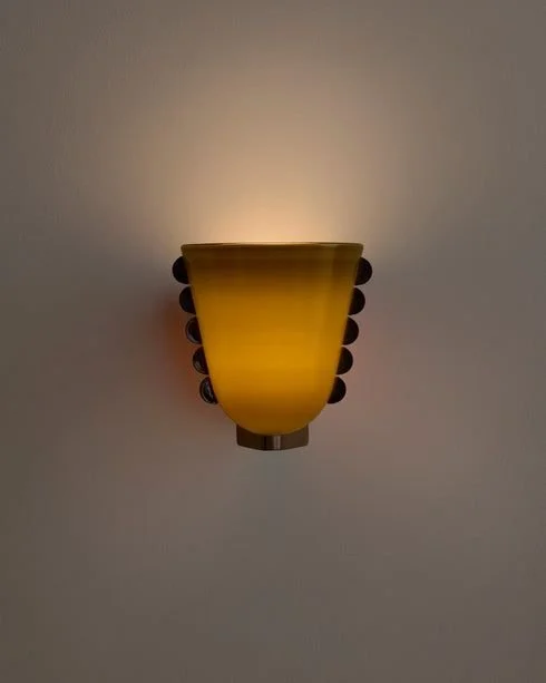 Wall-mounted yellow lamp with rounded black accents on a plain white wall