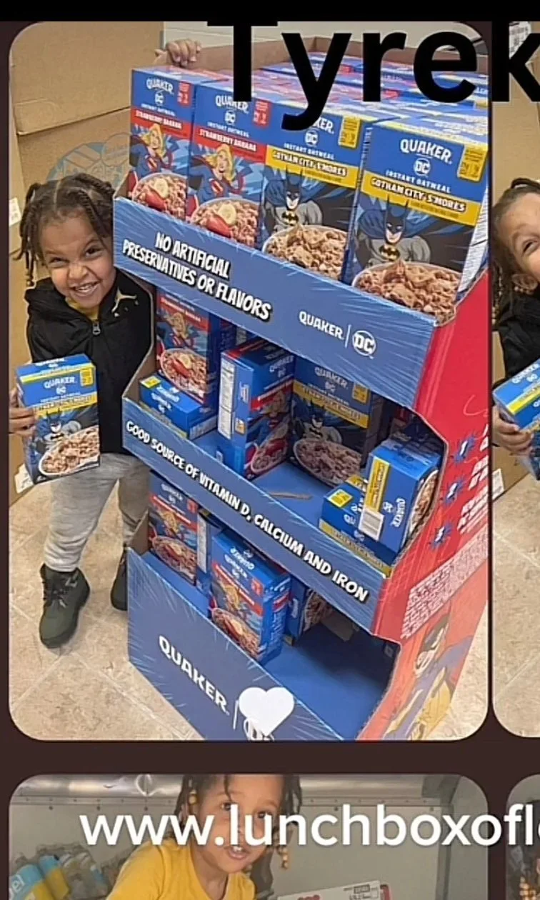 Two young girls smiling and holding Quaker oatmeal cereal boxes next to a retail display of Quaker oatmeal products featuring Batman branding from DC Comics.