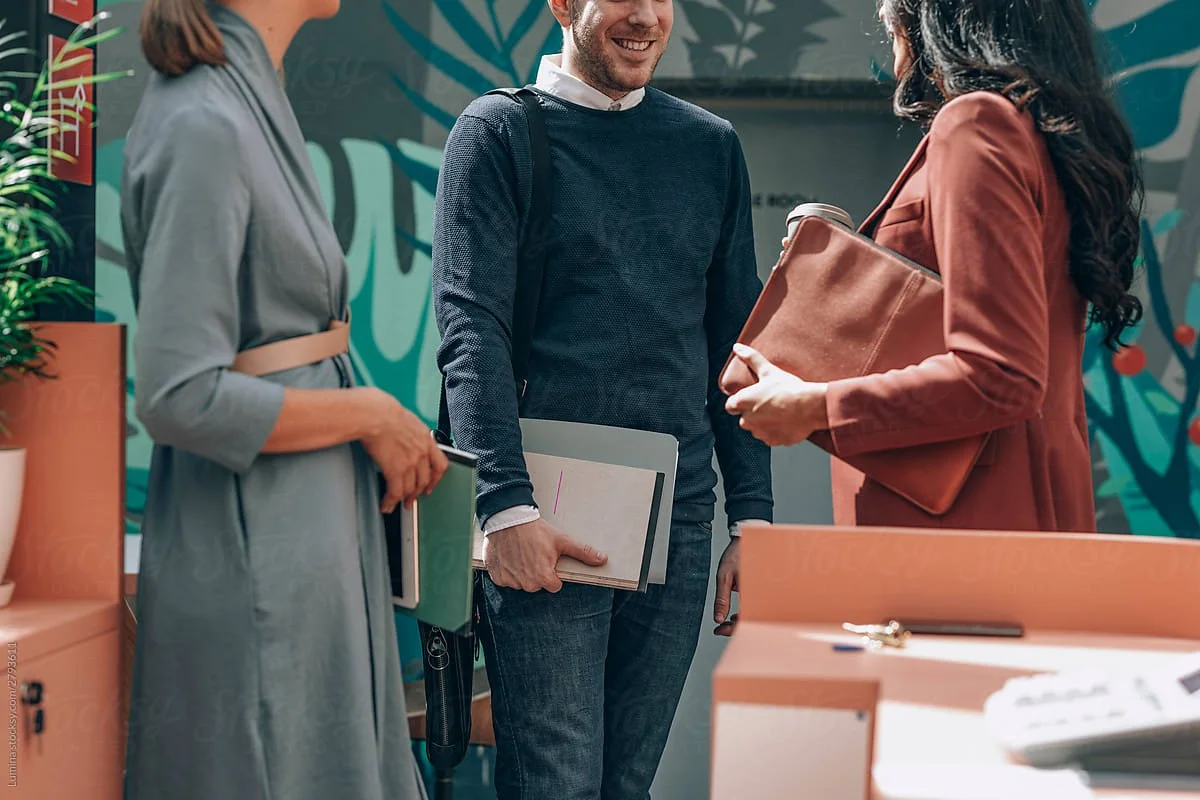 Three people having a conversation inside a modern office or lobby.