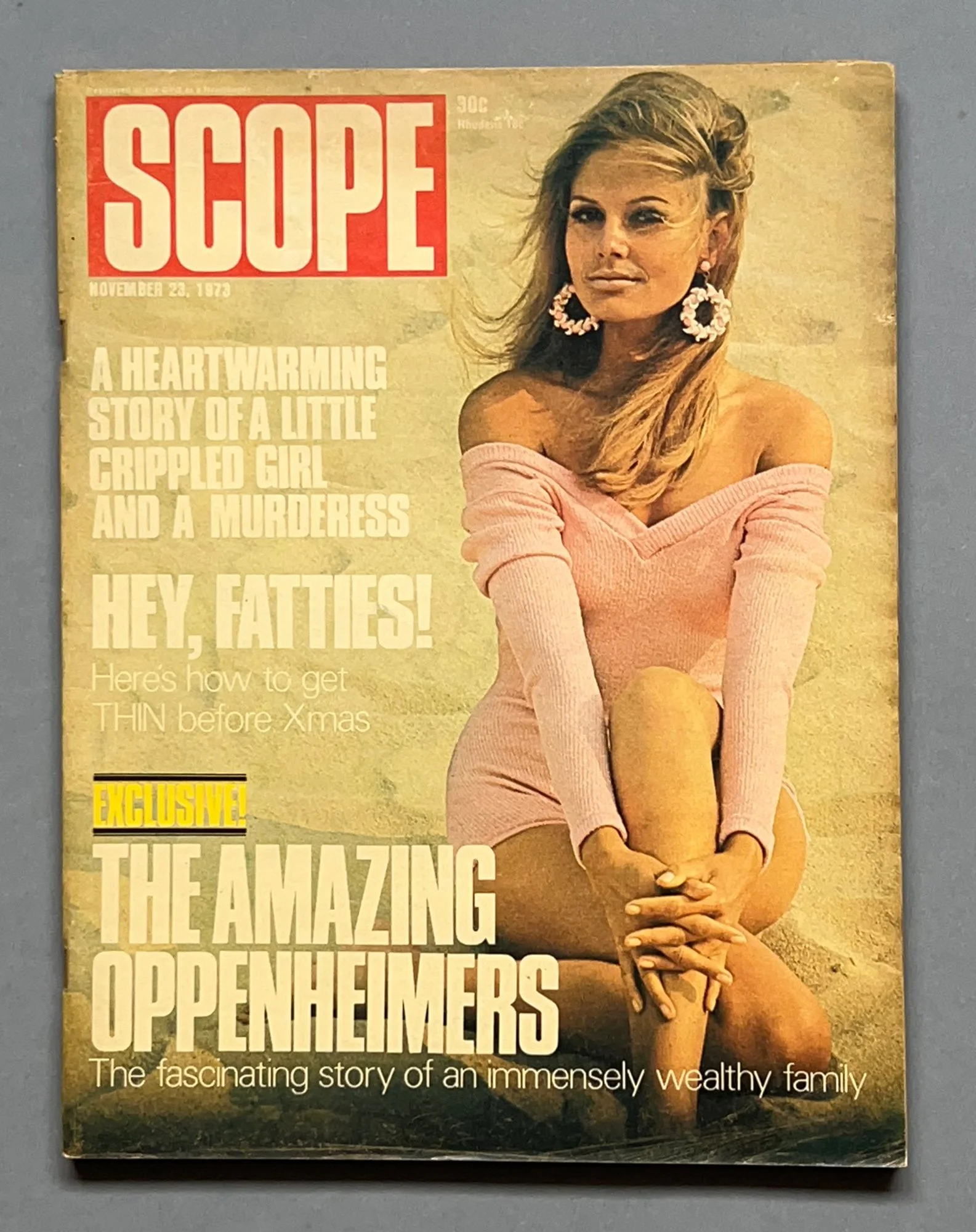 Vintage magazine cover of 'Scope' dated November 23, 1973, featuring a woman with long blonde hair wearing large earrings and a pink off-the-shoulder sweater dress, sitting on the ground with her hands clasped around her knee.