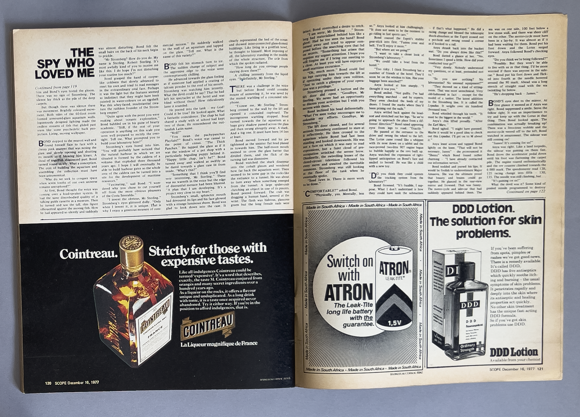 A two-page magazine spread, with the left page featuring an article titled "The Spy Who Loved Me" with multiple columns of text and a black advertisement for Cointreau orange liqueur at the bottom. The right page contains two black-and-white product 
