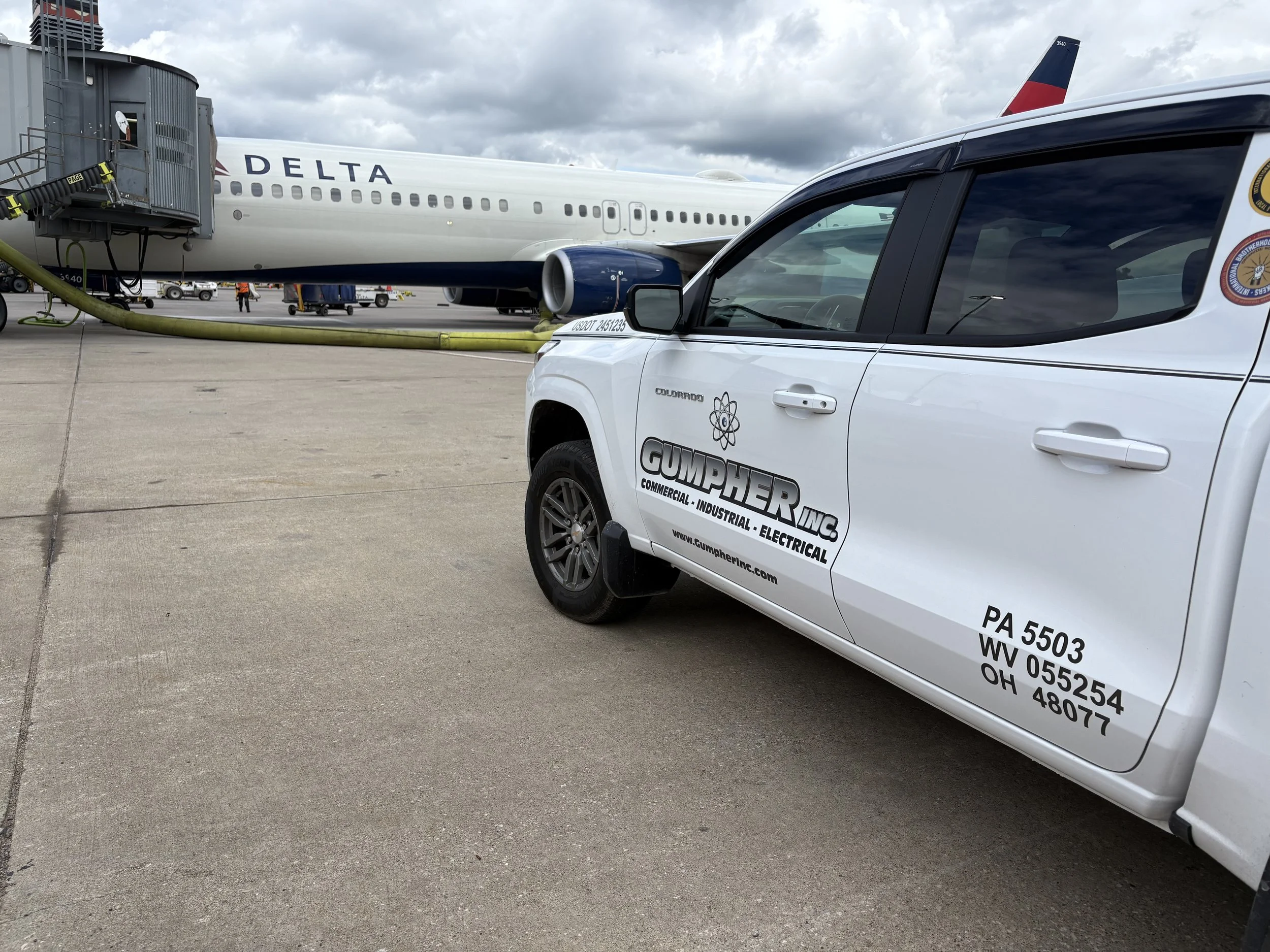 Commercial airplane parked at the airport gate connected to jet bridge, with service vehicle in the foreground