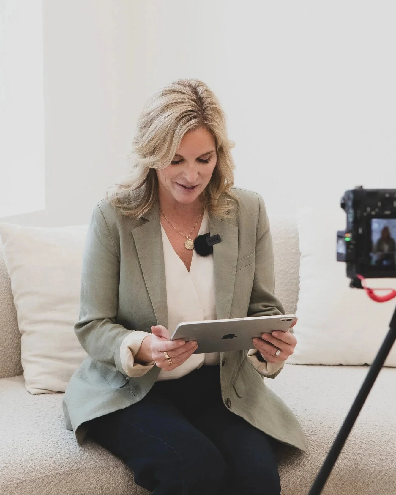 Woman recording interview on tablet with camera in a bright room.