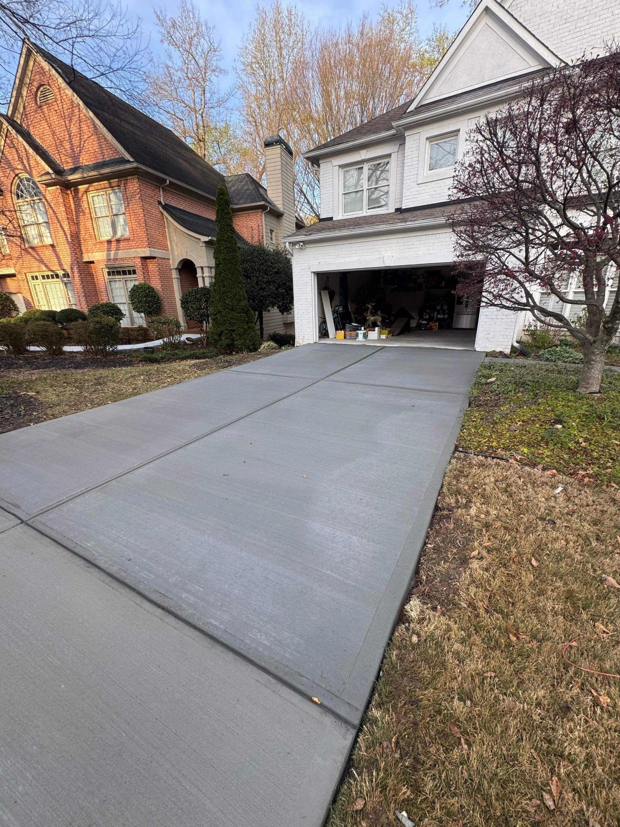 Clean, finished residential concrete driveway replacement showing a flawless broom finish and perfect grading.