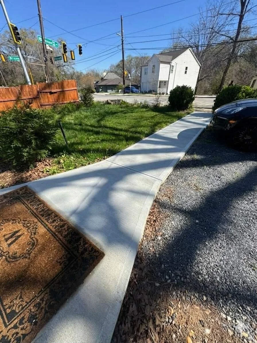 Clean, straight residential concrete sidewalk and walkway installation with a smooth broom finish.