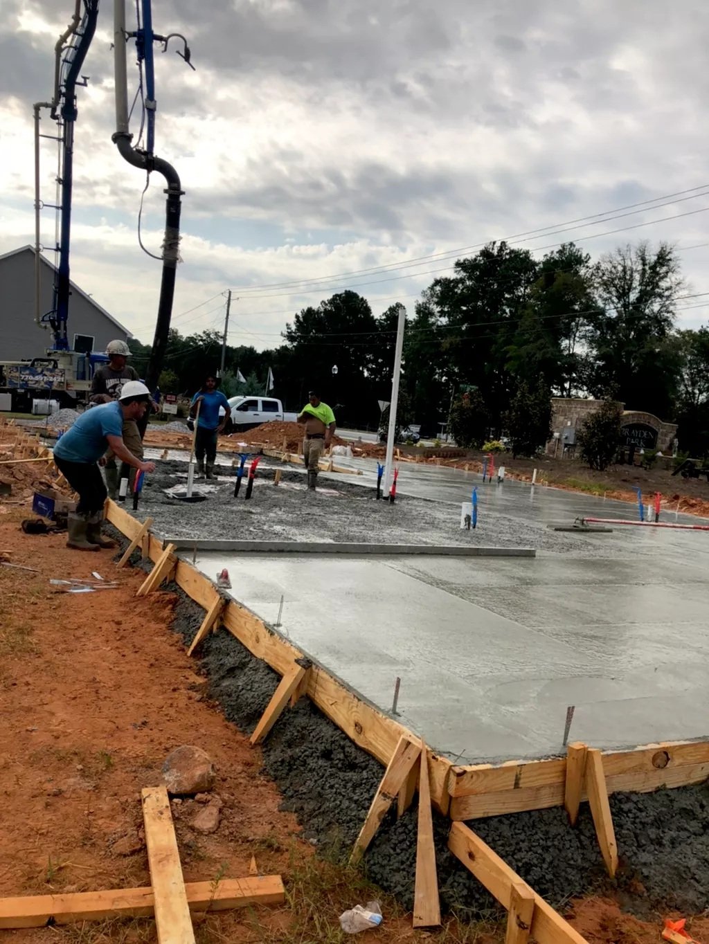 Construction workers pouring and leveling concrete for a building foundation on a construction site.
