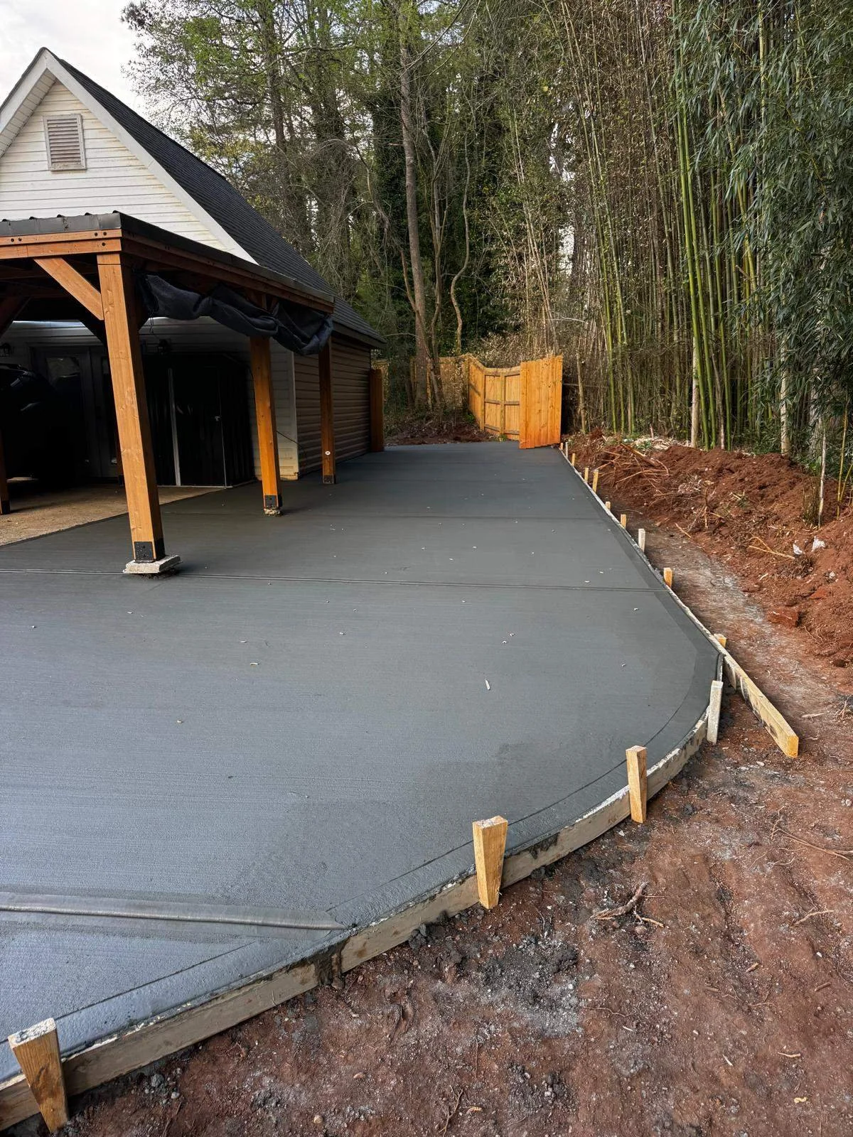 Freshly poured custom concrete driveway extension with smooth curved edges and wooden forms in Atlanta.