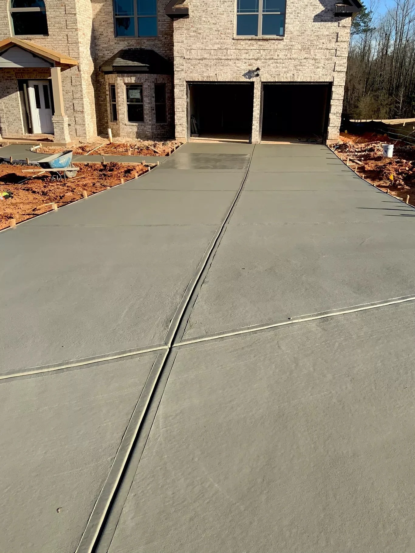 Newly installed large residential concrete driveway featuring precise center control joints leading to a multi-car garage.