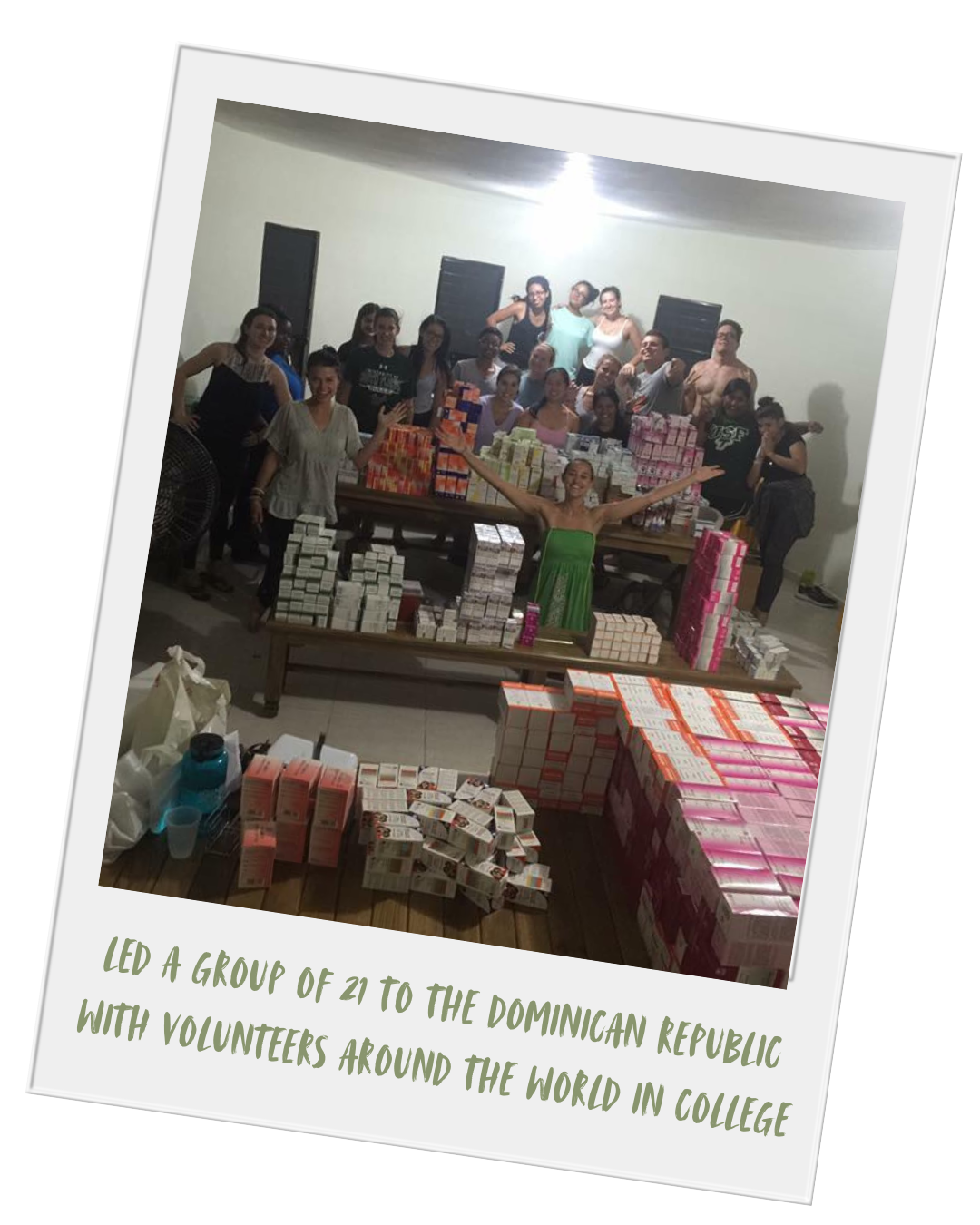 Group of people standing behind large stacks of boxes and cartons in a room, smiling and posing for the photo, with a caption indicating they led a charitable project in the Dominican Republic.