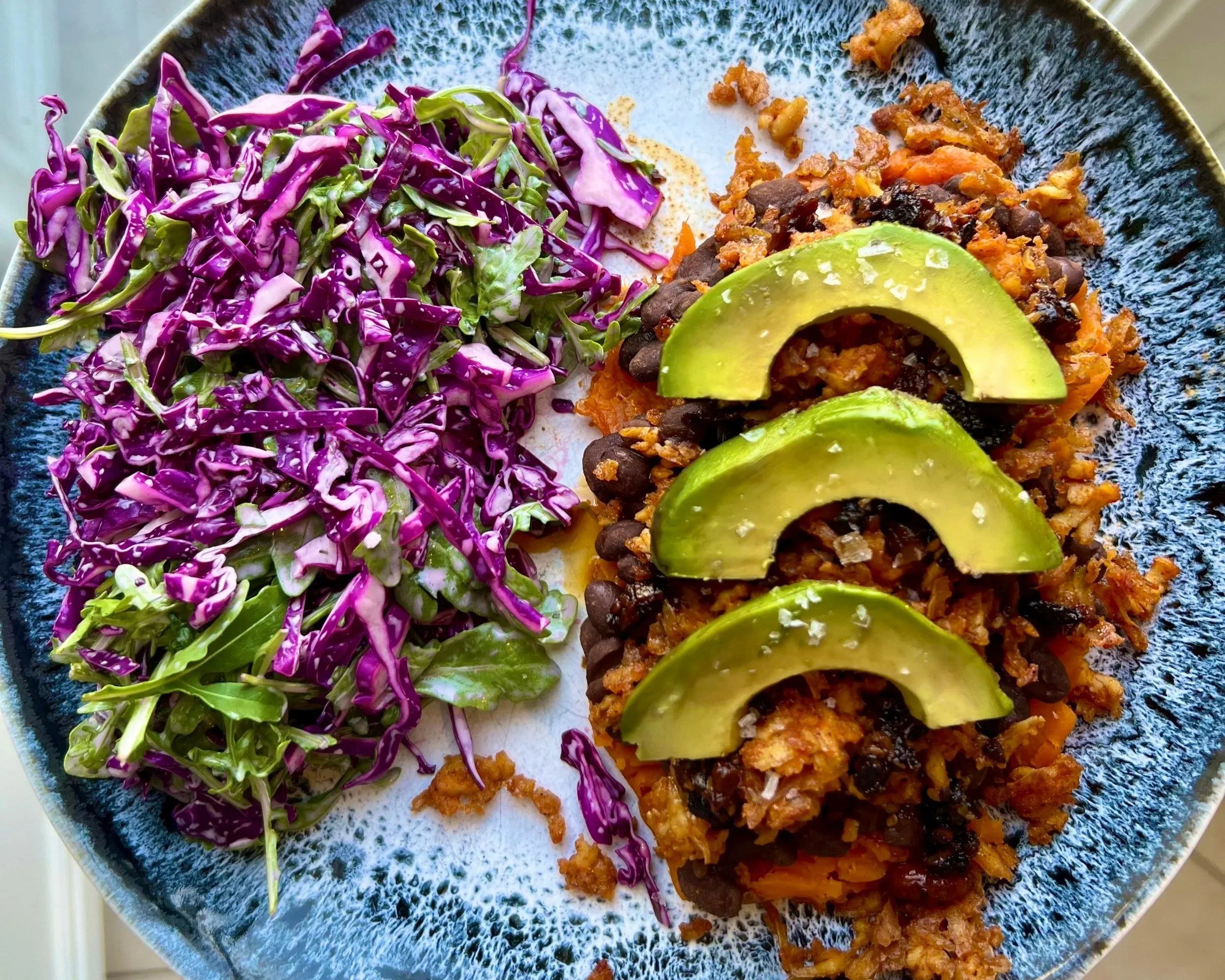 Image of sweet potato with tofu, black beans, and avocado with a side salad