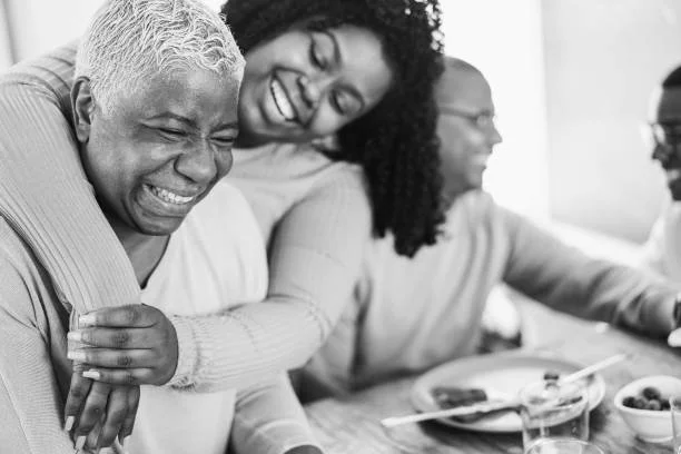 Group of three women sitting at a table, smiling and enjoying each other's company, with plates of food and drinks in front of them.