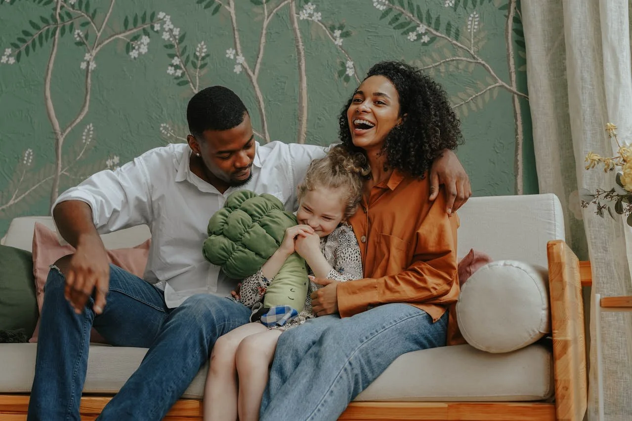 A happy family sitting on a sofa in a warmly decorated room, sharing a joyful moment.