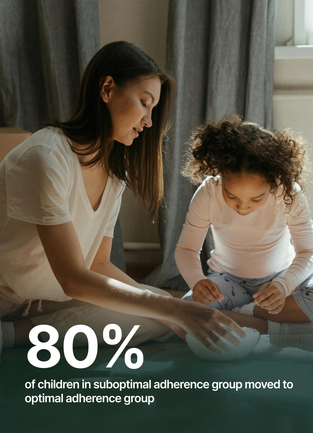 A woman and a young girl sitting on the floor, engaging in an activity together in a cozy room with curtains and a window in the background.