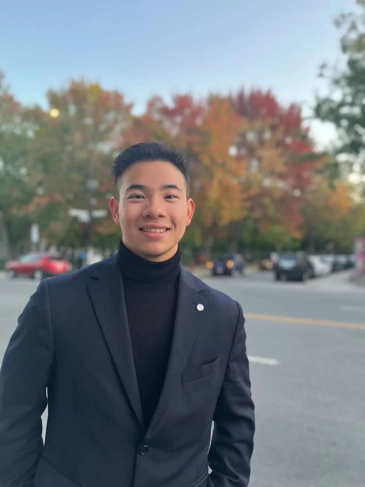 Homme aux cheveux noir portant un costume noir.